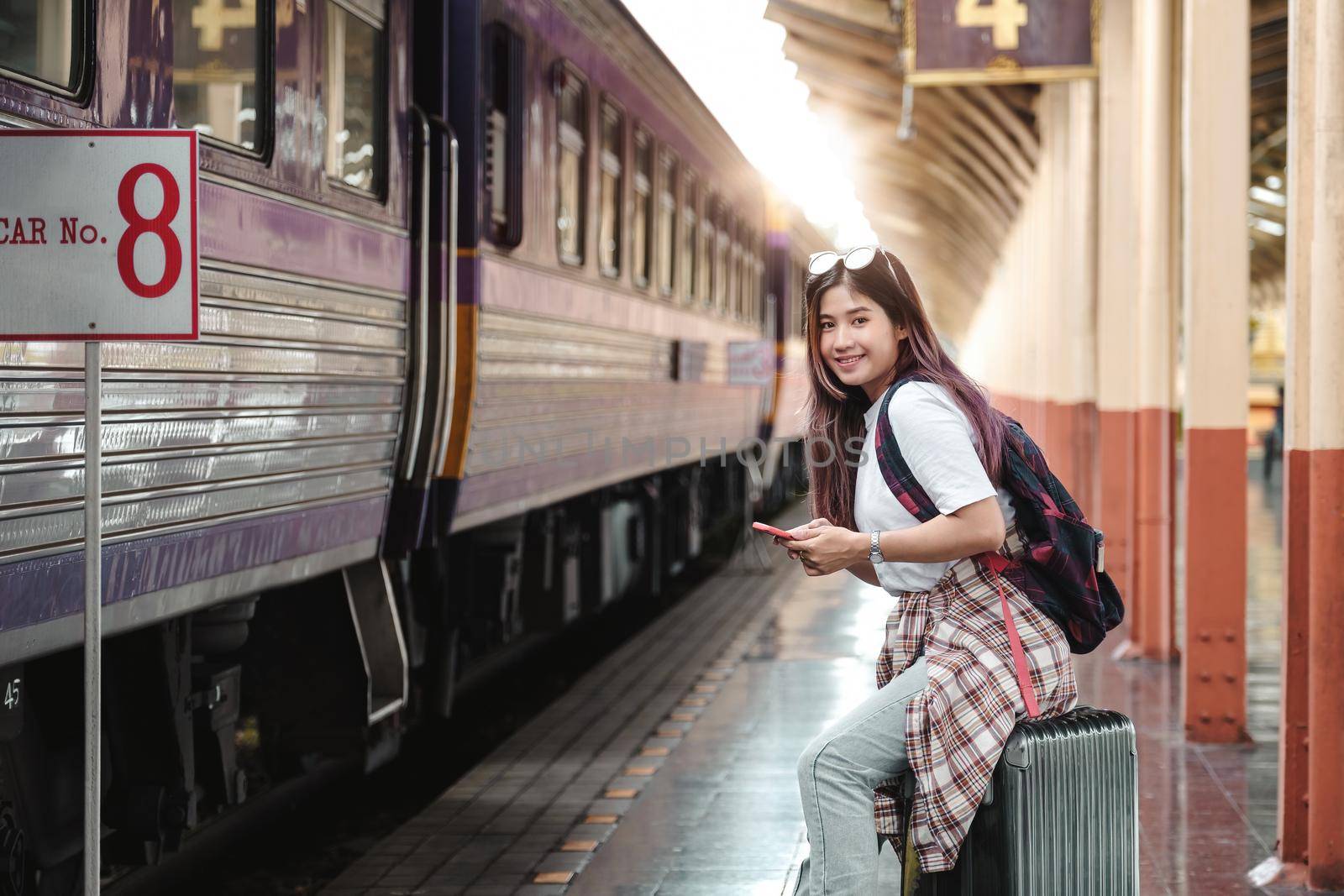 Portrait attraction asian Woman traveler tourist sitting with luggage at train station. Active and travel lifestyle concept. by nateemee