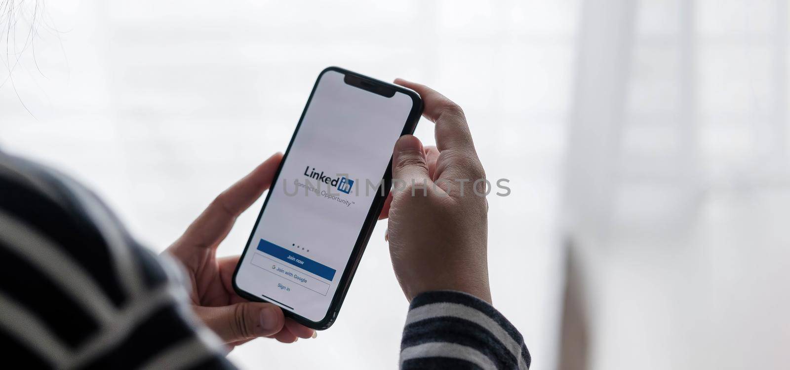 CHIANG MAI, THAILAND, JUL C12, 2021 : A women holds Apple iPhone Xs with LinkedIn application on the screen.LinkedIn is a photo-sharing app for smartphones..