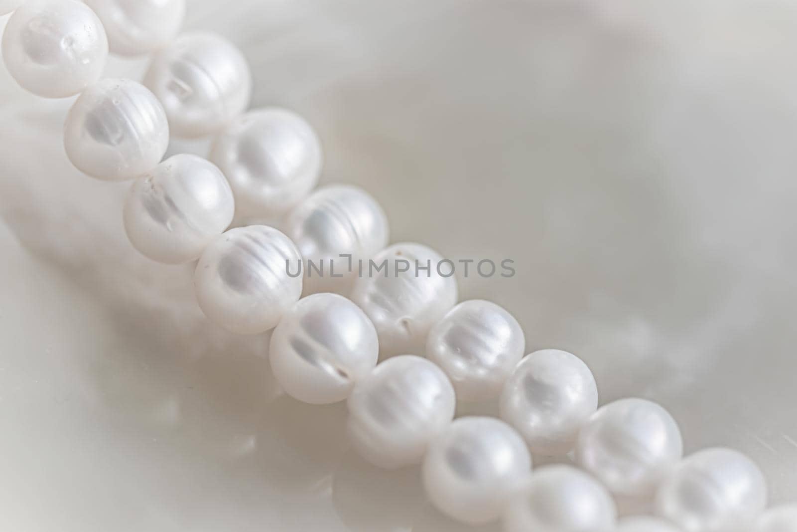 Nature white string of pearls on marble background in soft focus, with highlights