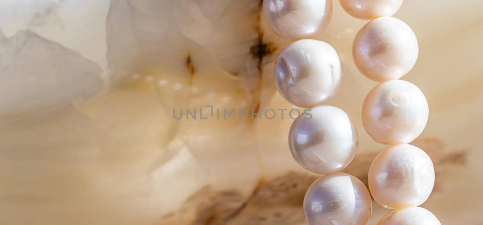 Nature white string of pearls on marble background in soft focus, with highlights.