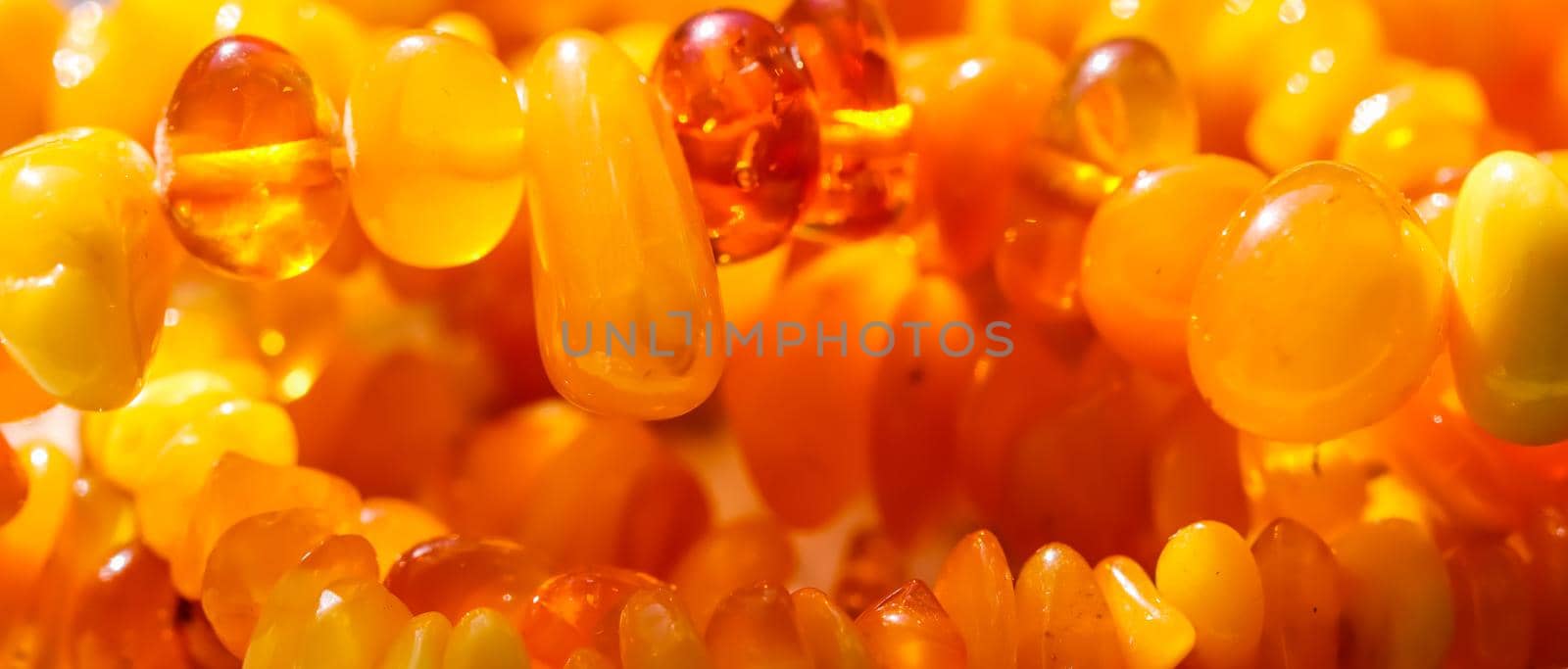 Sunny beads of fire amber. Natural gemstone background, jewelry concept by Olayola