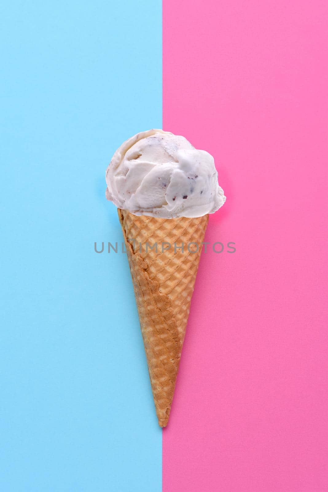 A Chocolate Chip Ice Cream Cone on a blue and pink background. Flat lay minimalist styling. 