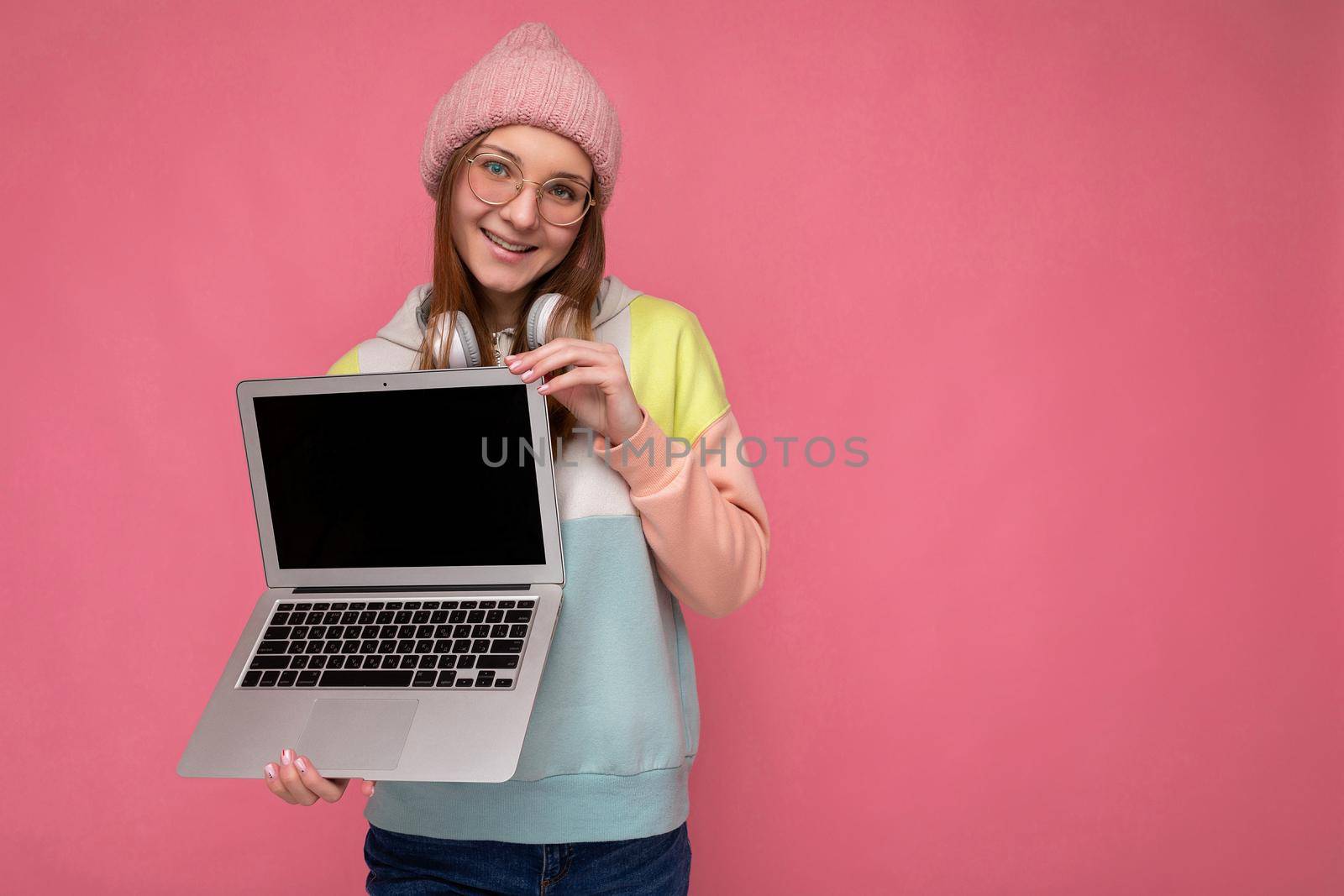 Photo of beautiful young girl holding computer laptop looking at camera isolated over colourful background by TRMK
