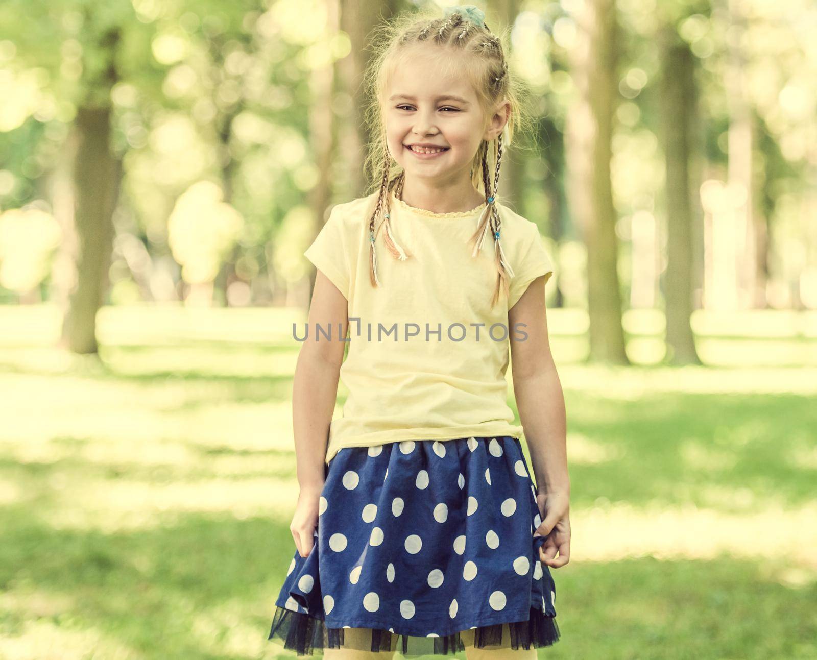 cute little girl smiling in the morning park. blurred background
