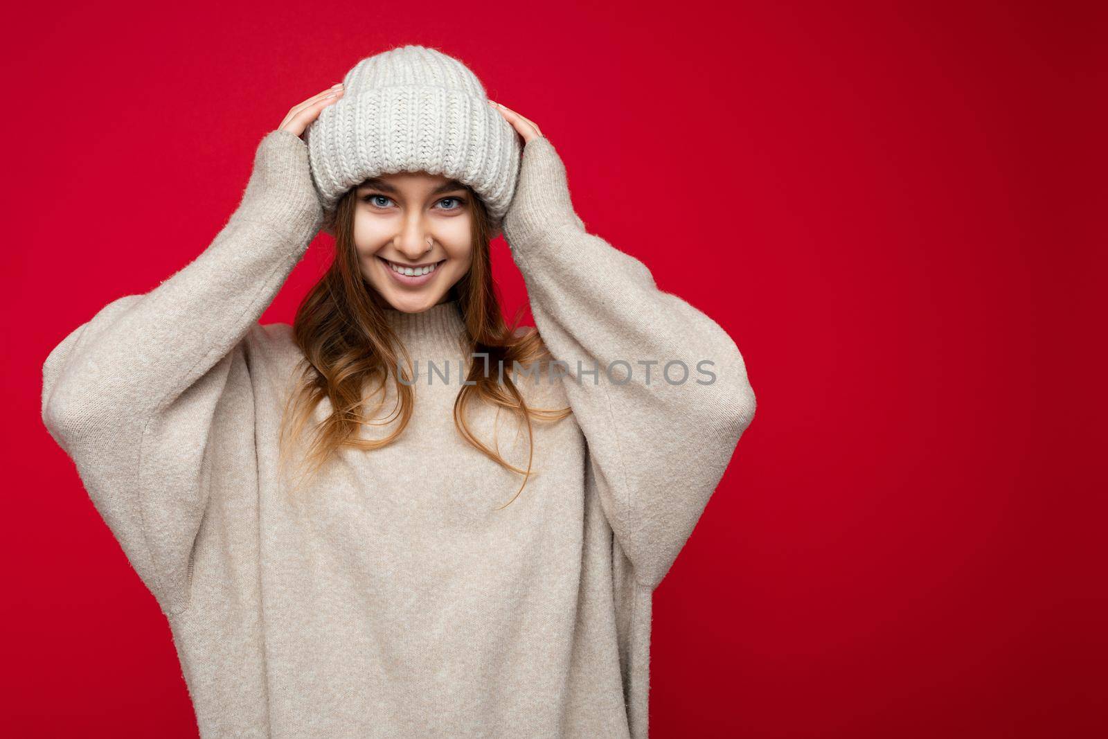 Attractive smiling happy young dark blond woman standing isolated over colorful background wall wearing everyday stylish outfit showing facial emotions looking at camera. Empty space