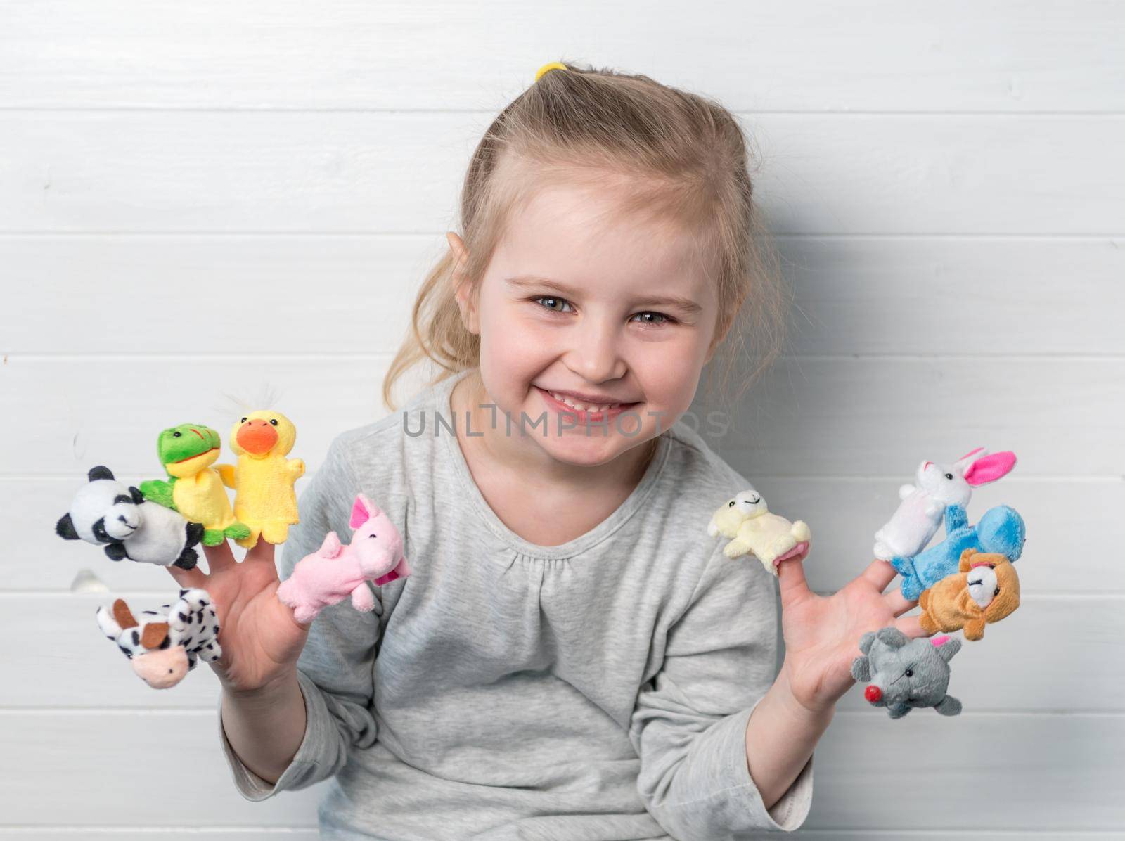 Lovely small girl with doll puppets on her hands, smiling and playing