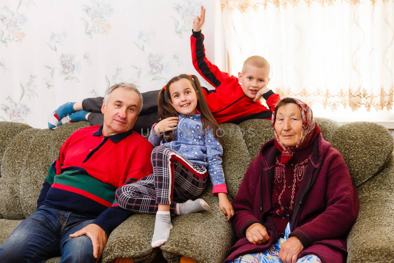 Grandchildren jumping on couch with their grandparents in the living room