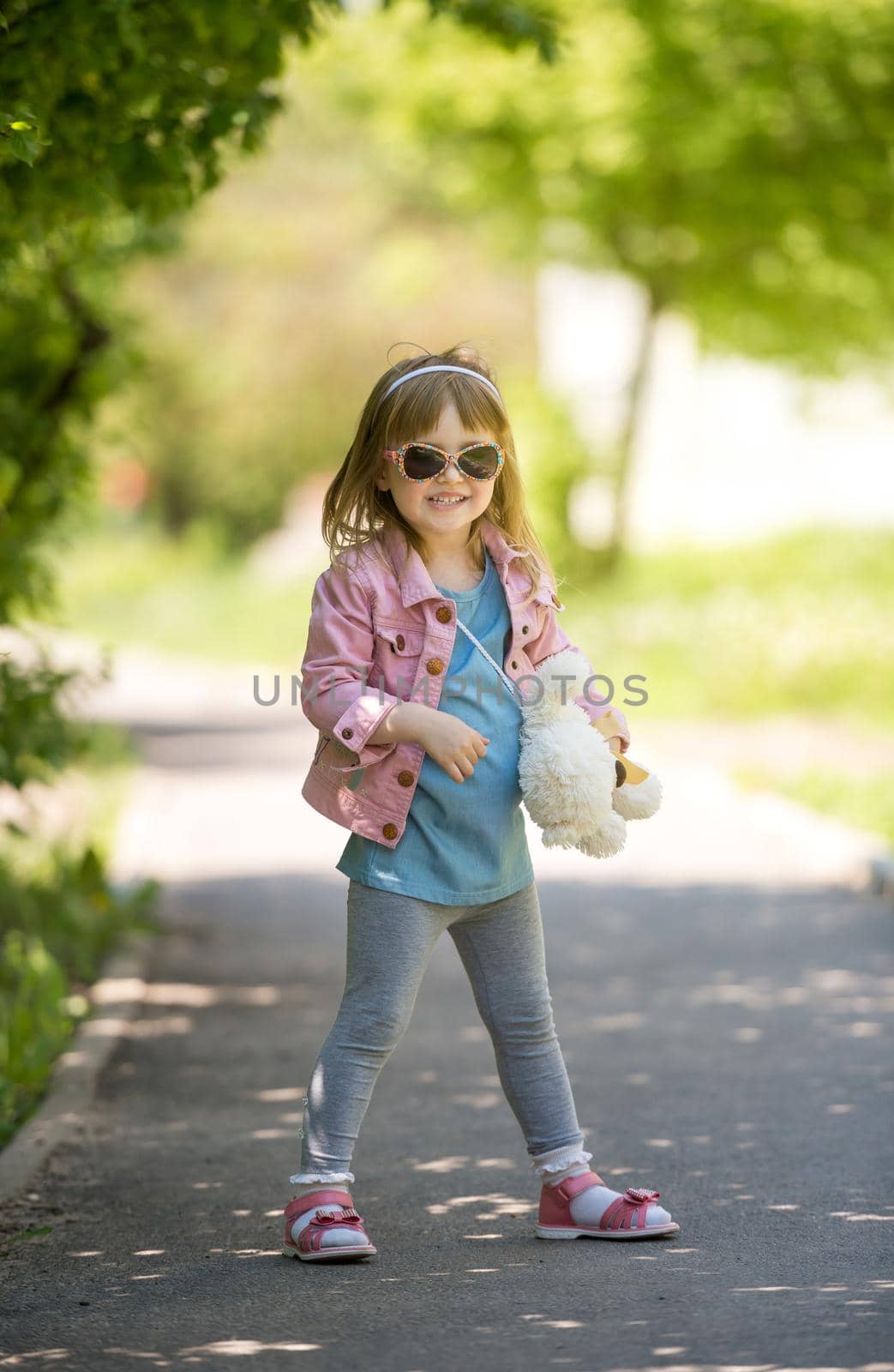 smiling little girl with sunglasses walking in spring park