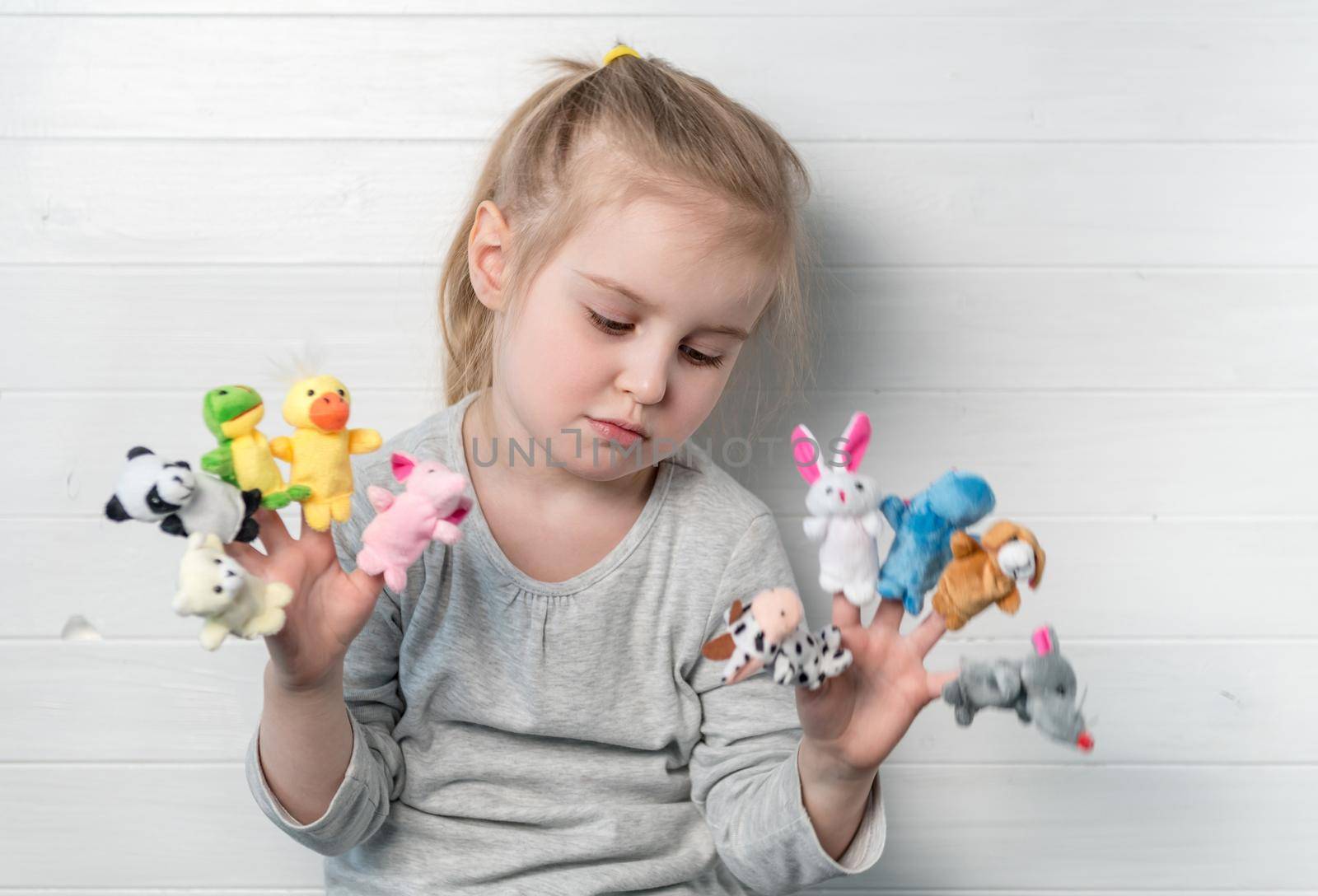 Lovely sad small girl with doll puppets on her hands, smiling and playing