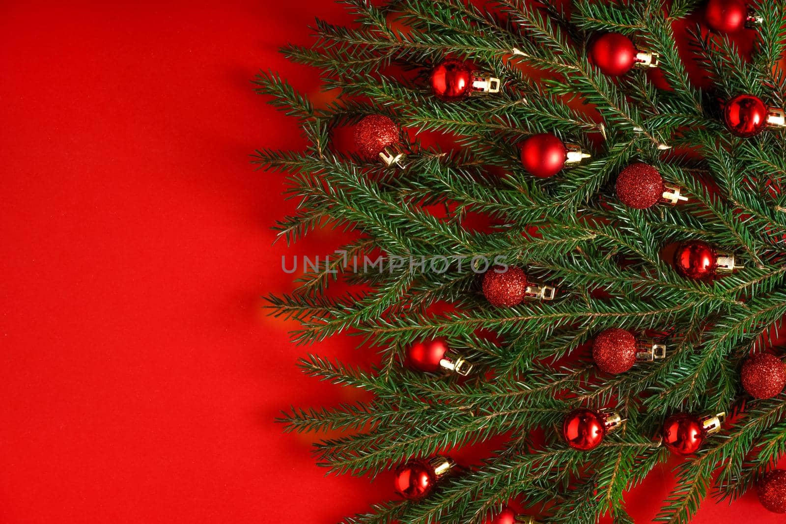 Christmas tree made of green coniferous branches on a red background. Christmas background with place for text. Christmas holiday concept. Ball toys. Copy space by A_Gree