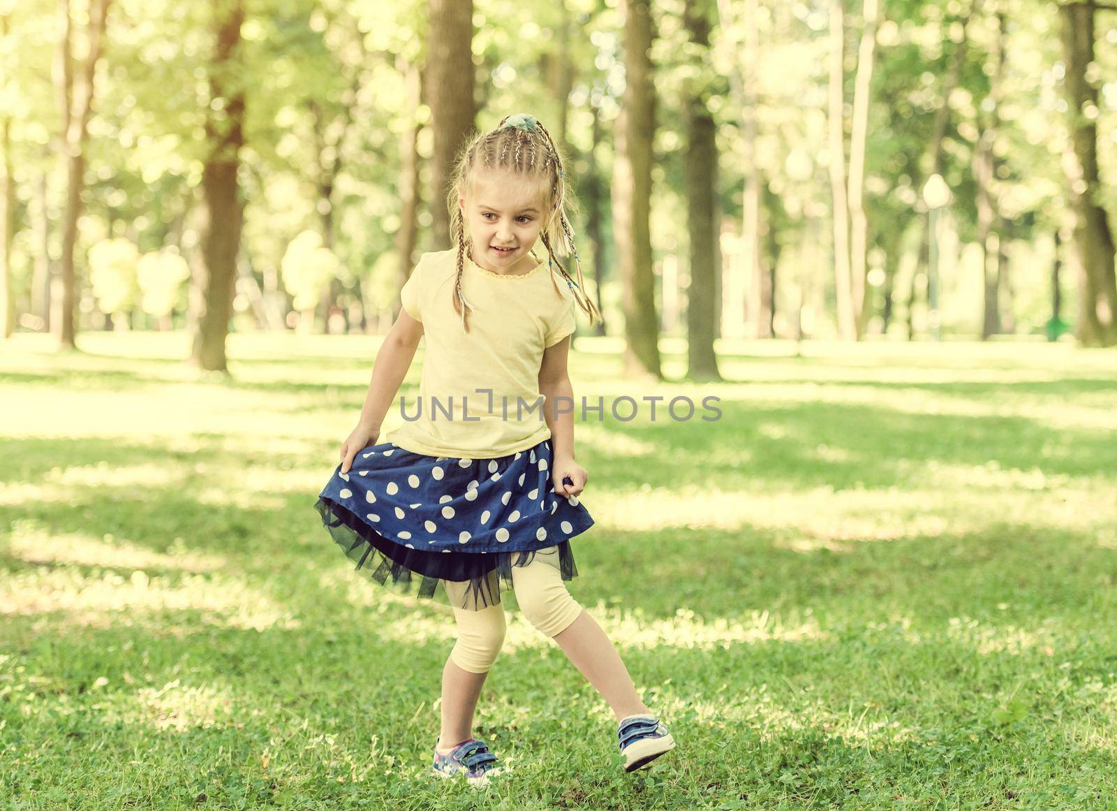 cute little girl have a fun in the morning park. blurred background