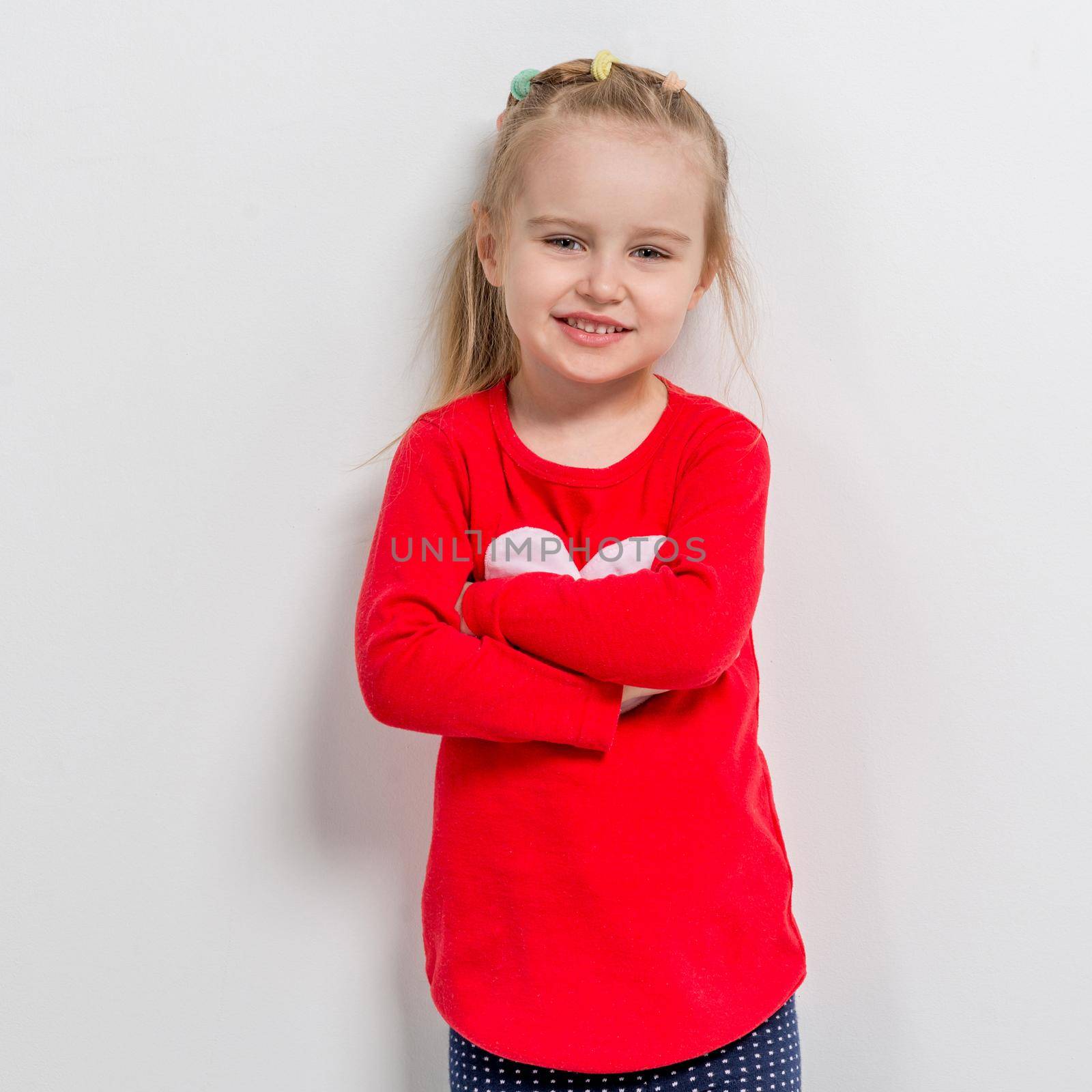 cute laughing little girl in red sweater with her arms folded