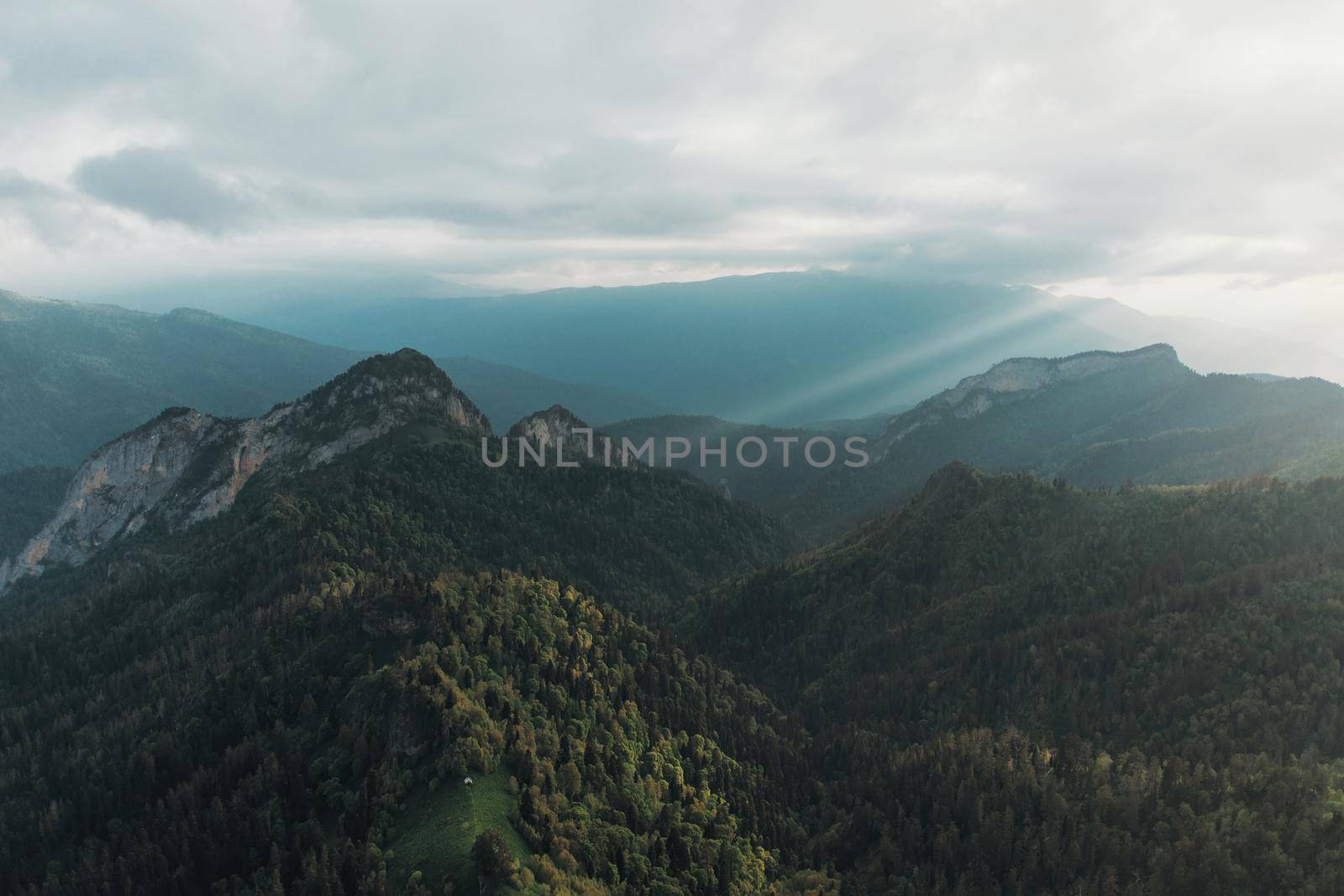 Sunbeams over mountains in cloudy weather at sunset.