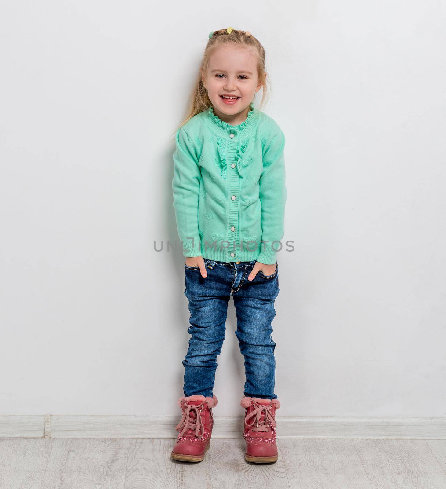 beautiful cheerful little girl with her hands in pockets of jeans