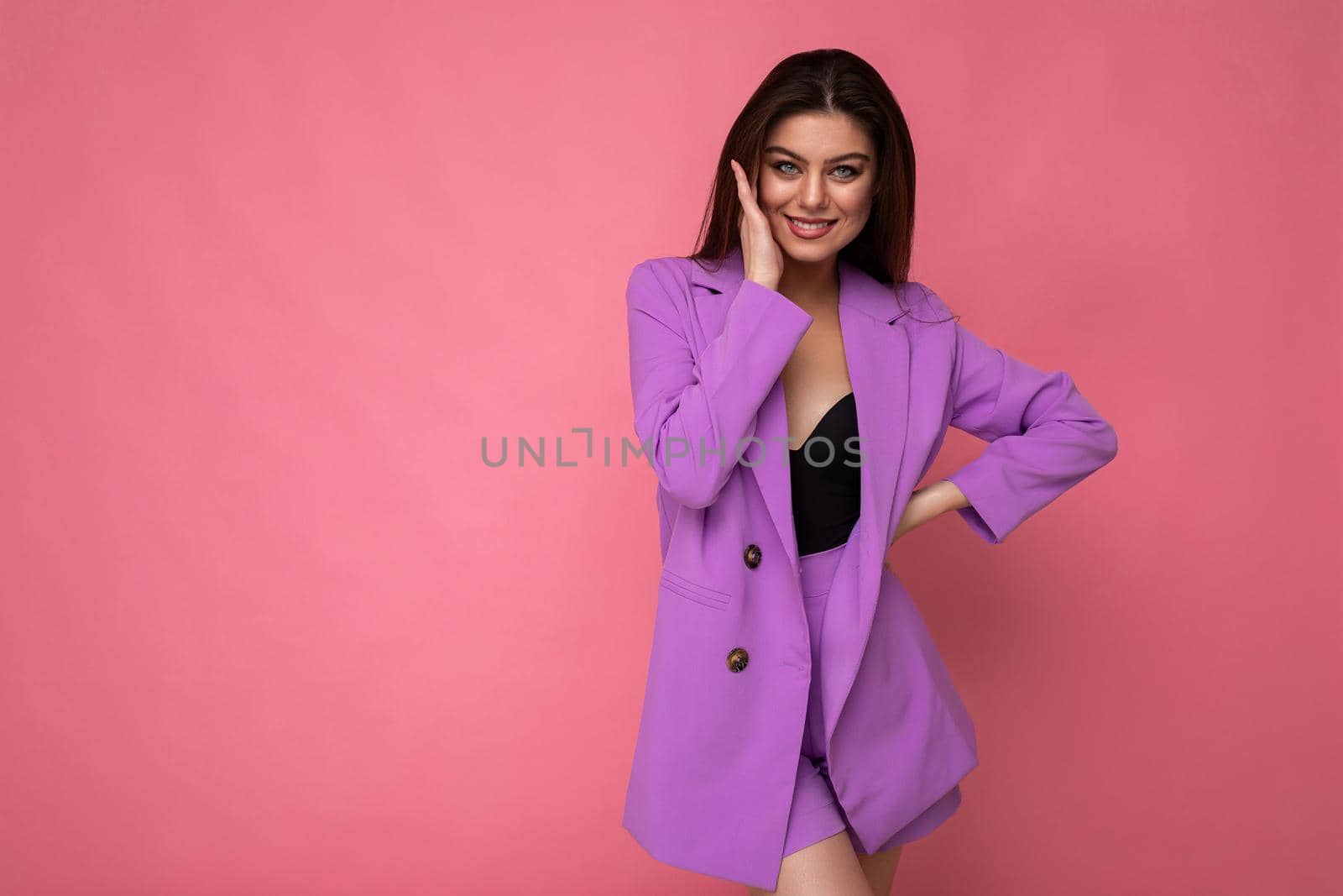 Young happy smiling brunette woman nice-looking attractive charming elegant fashionable wearing stylish suit with jacket isolated over pink background with copy space by TRMK