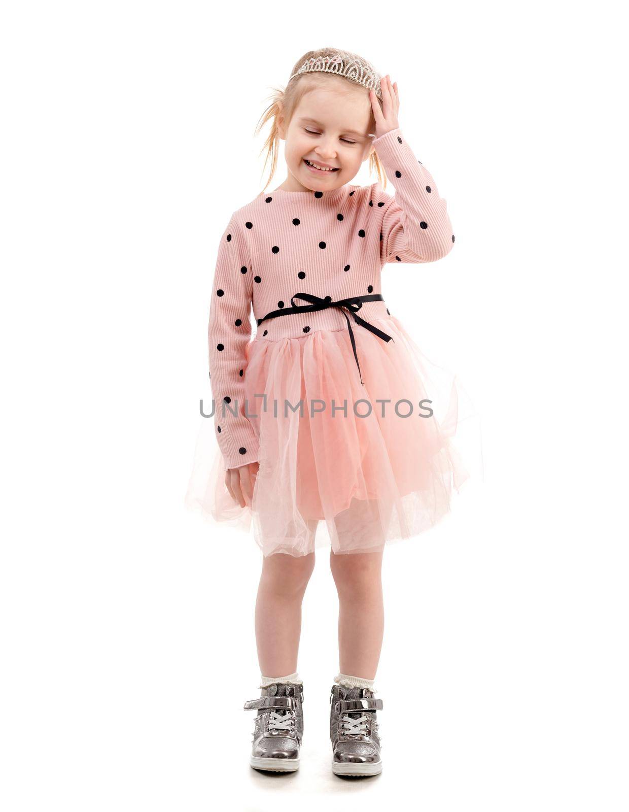 Lovely kid wearing a princess crown dressed in cute pink outfit, smiling widely