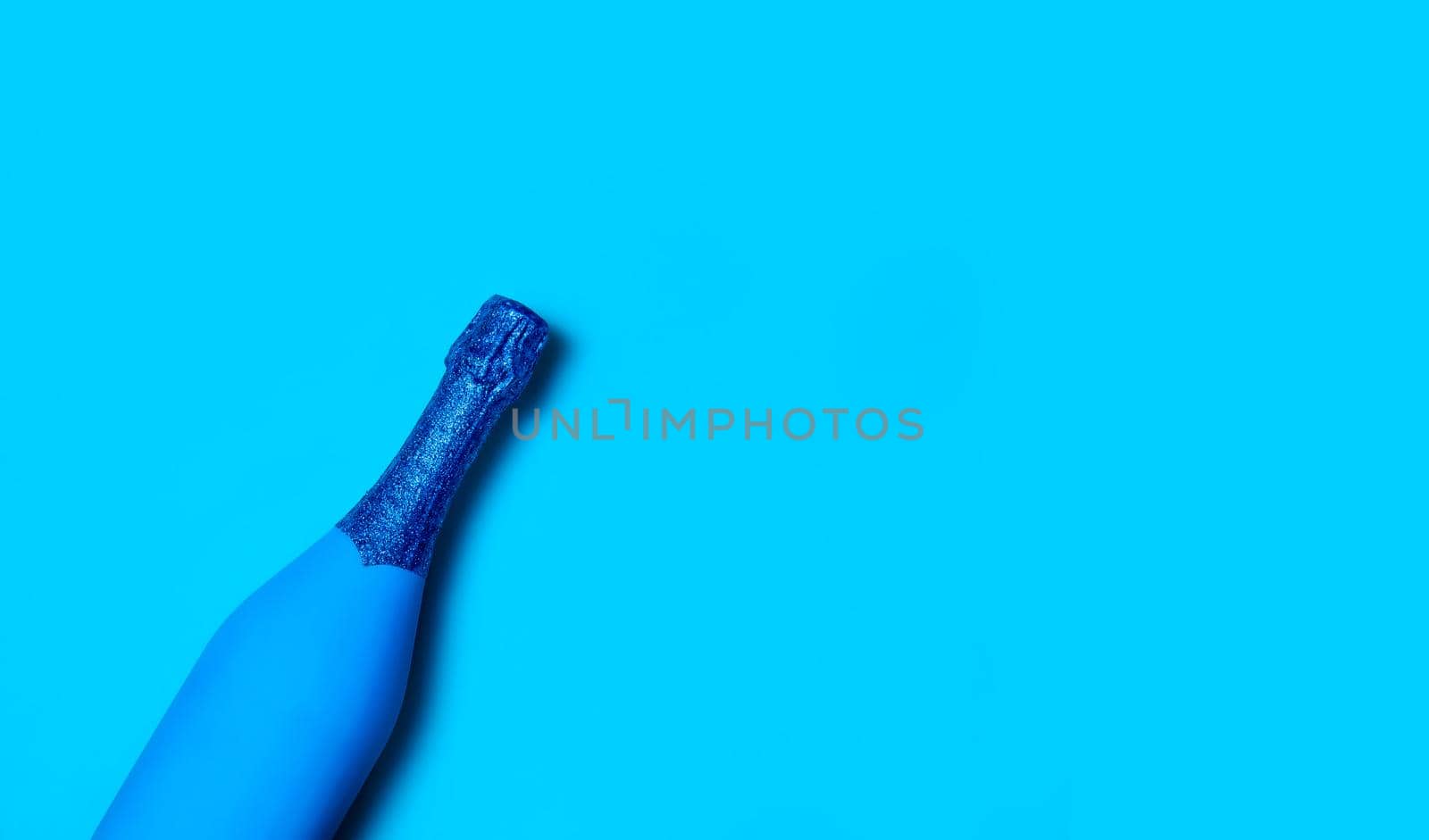 Festive Minimalistic Champagne Bottle on Blue Background. Creative Concept. Classic Blue - Color of the year 2020. Top View. Copy Space For Your Text