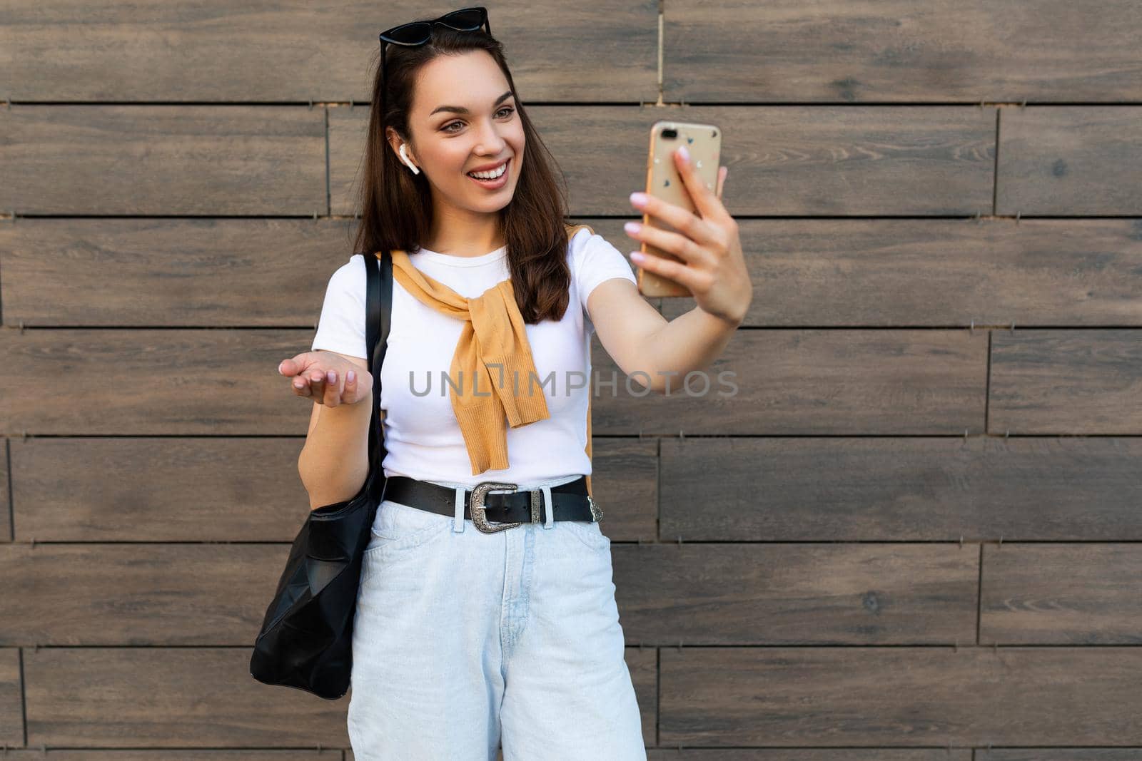 Photo of beautiful young woman wearing casual clothes standing in the street having communication via mobile phone looking at smartphone and having fun and good mood.Copy space