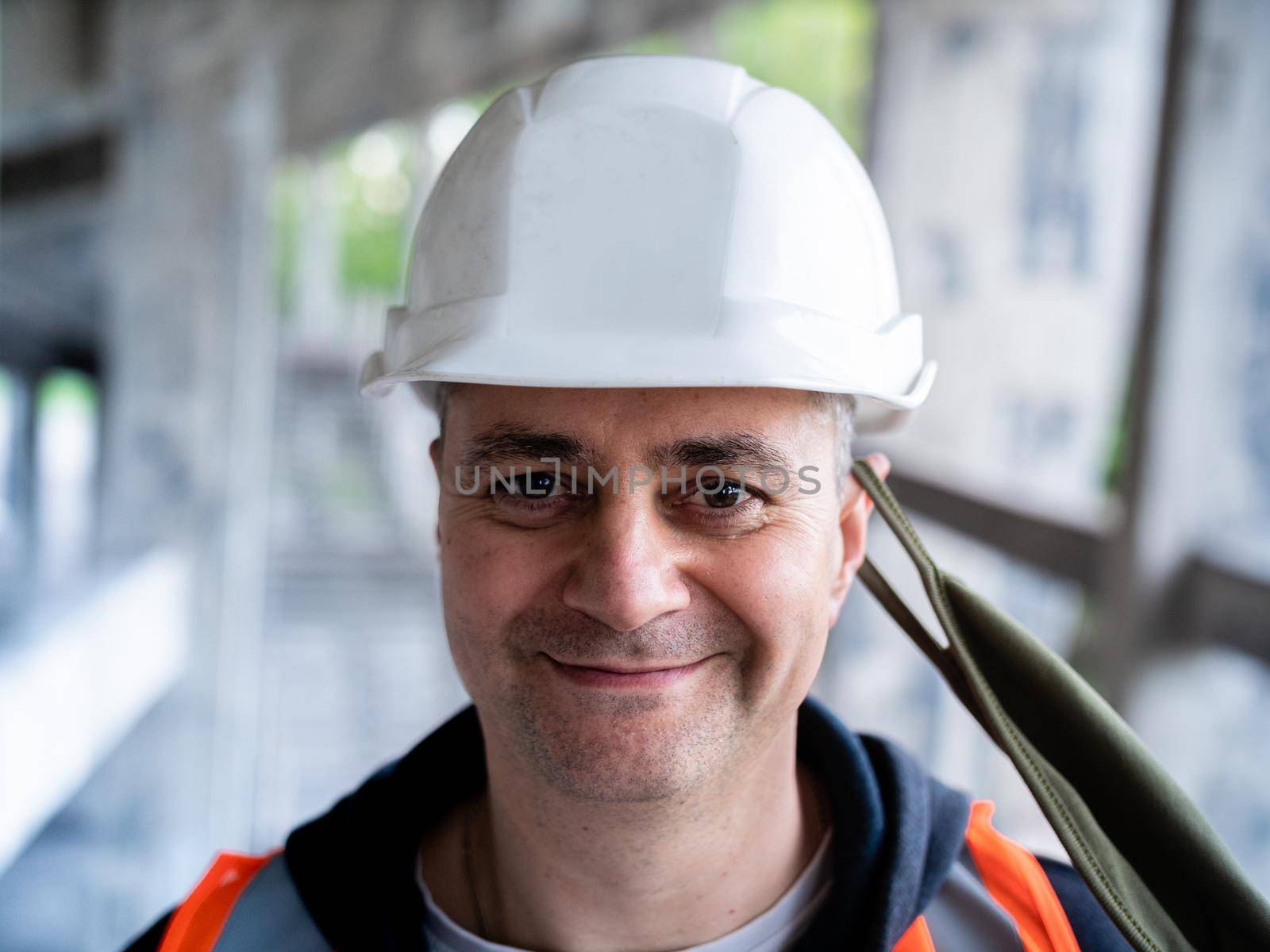 Portrait of a male Builder in a construction helmet and a medical antiviral mask. The man removes the protective mask from his face to symbolize the end of the pandemic.