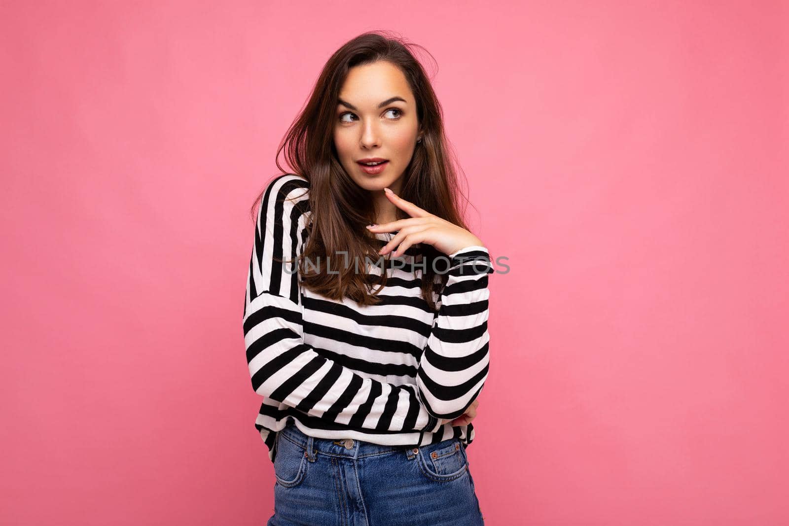 Photo shot of cute attractive pretty thoughful dreaming young brunette woman wearing casual striped longsleeve isolated over colorful background with copy space.