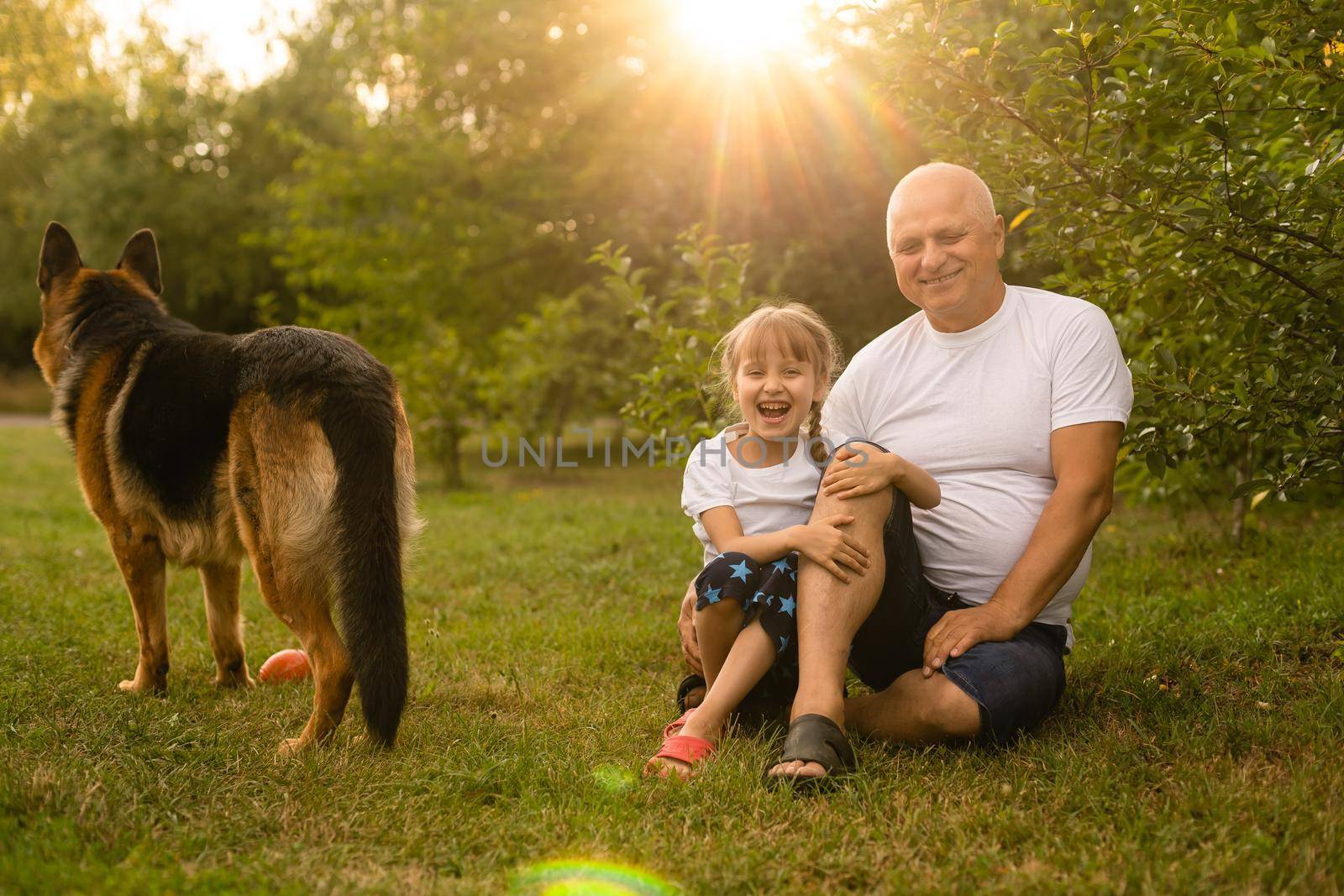 Grandfather with granddaughter and a dog in the garden