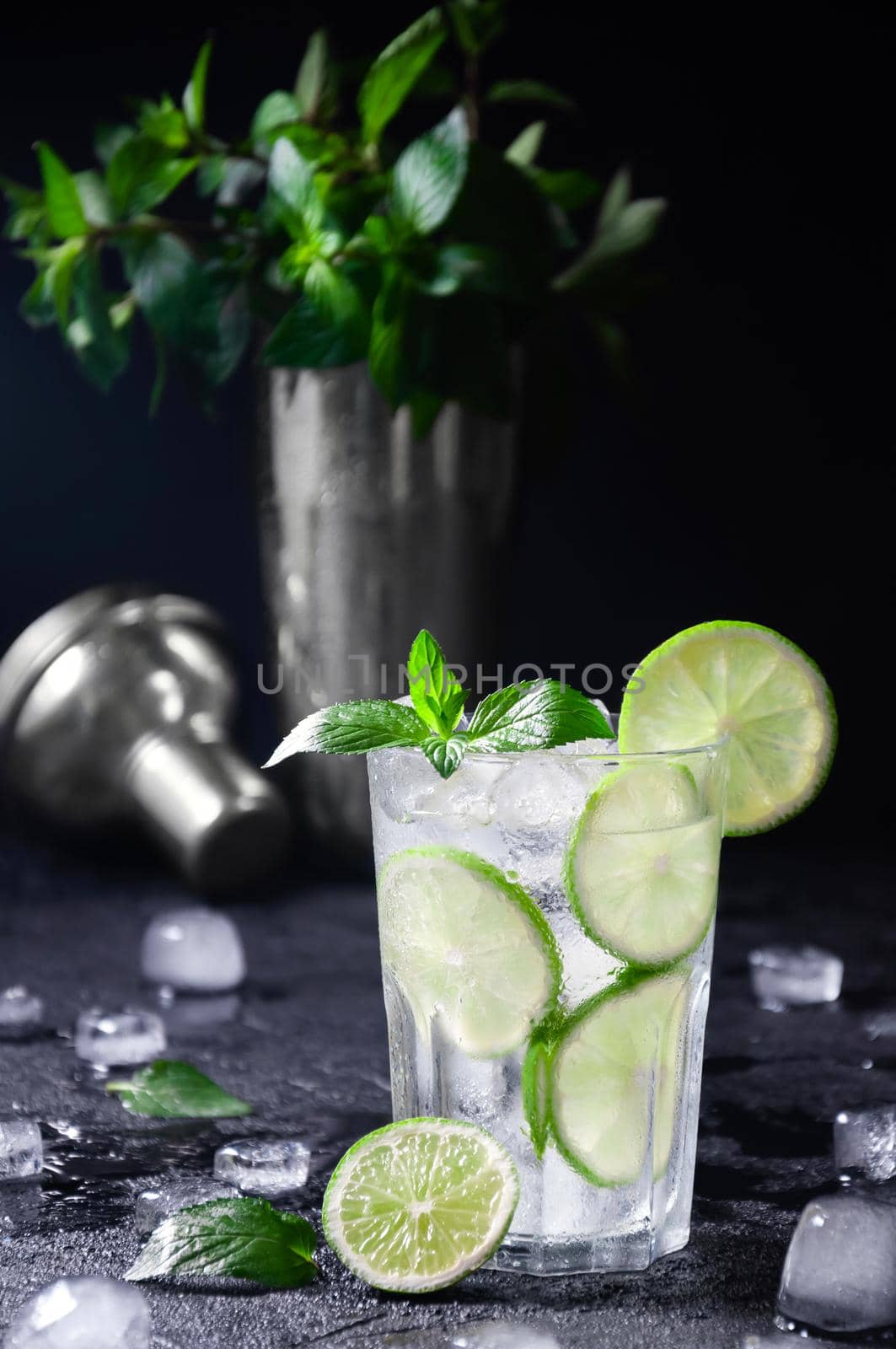 Cocktail Mojito or Lemonade with Lime, Mint and Ice on Dark Background. Concept Fresh Summer Drinks.