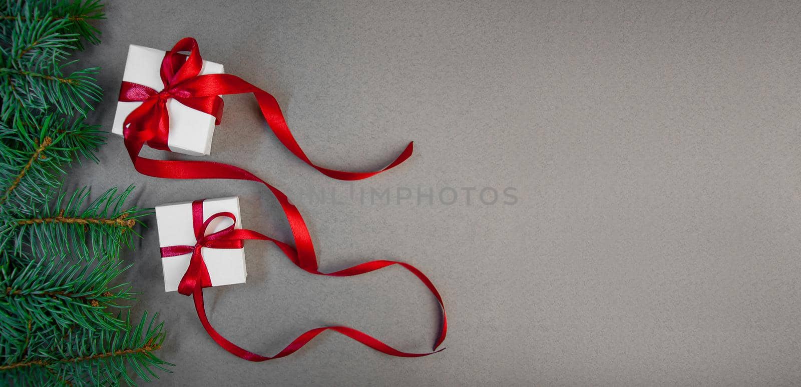 Christmas Gift in White Box with Red Ribbon Fir Tree Branches Dark Grey Background. New Year Holiday Composition. Banner. by Svetlana_Belozerova