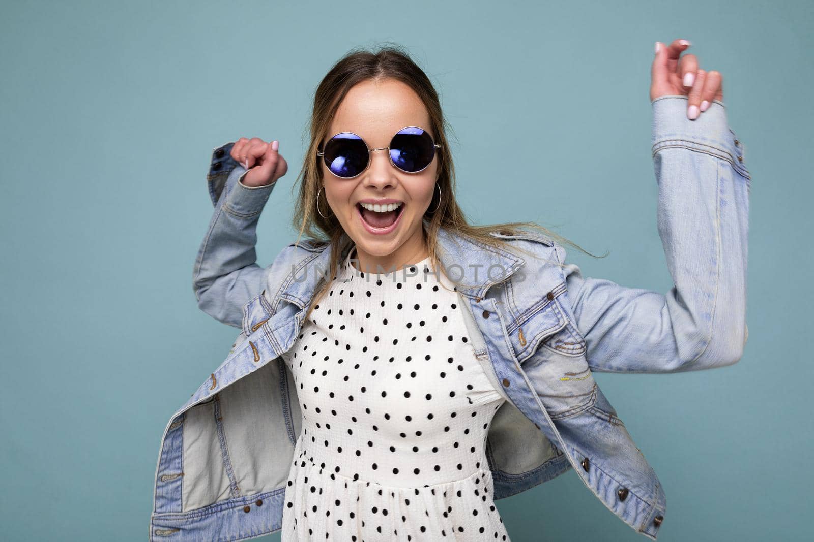 Photo shot of beautiful positive young blonde woman wearing summer casual clothes and stylish sunglasses isolated over colorful background looking at camera and having fun by TRMK