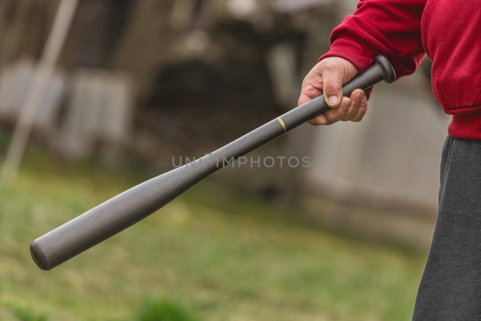 Man's hand holds baseball bat in the background of the street outdoors by AYDO8