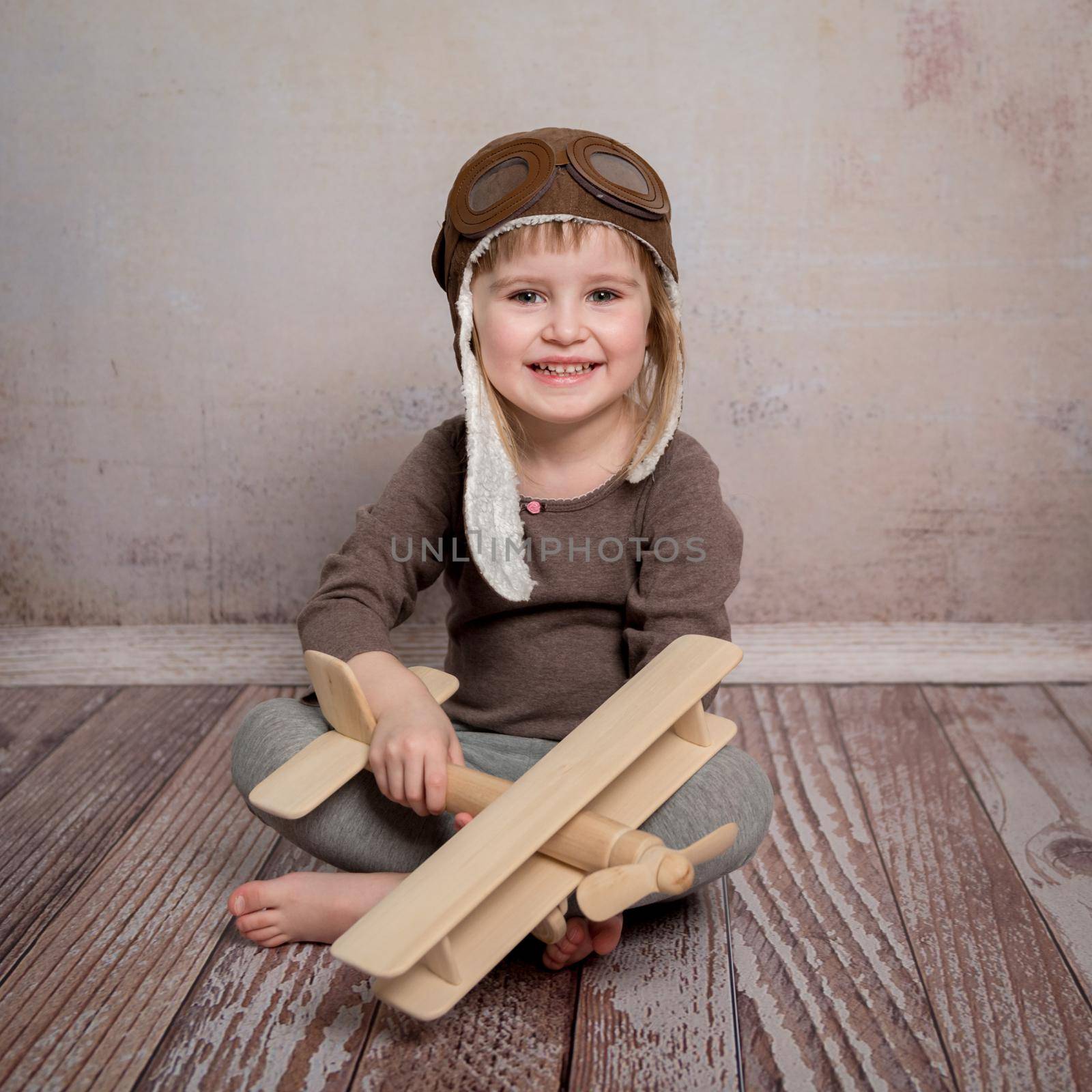 smiling little girl with wooden plane in hands by tan4ikk1