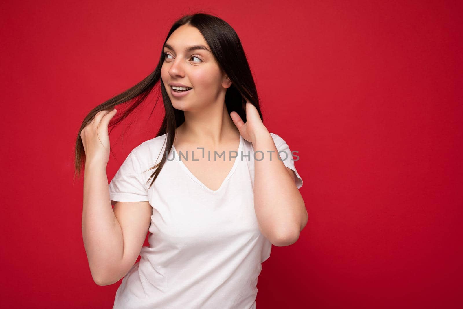 Shot of attractive happy smiling young woman wearing casual outfit standing isolated over colourful background with empty space looking to the side. Mock up.