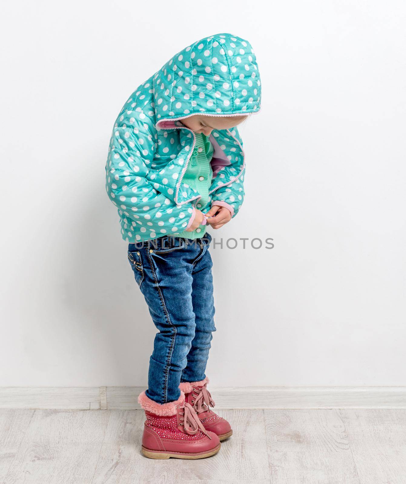 little girl fastening her blue jacket by tan4ikk1