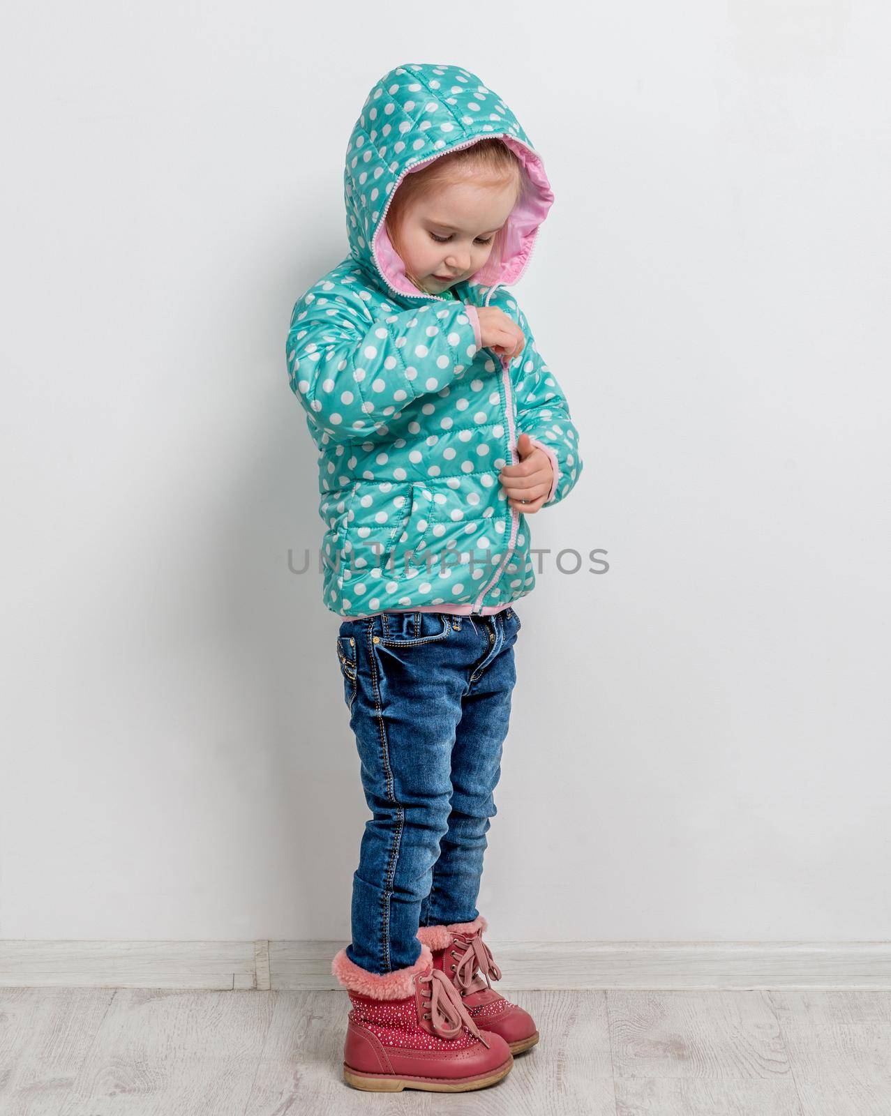little girl fastening her blue dotted jacket