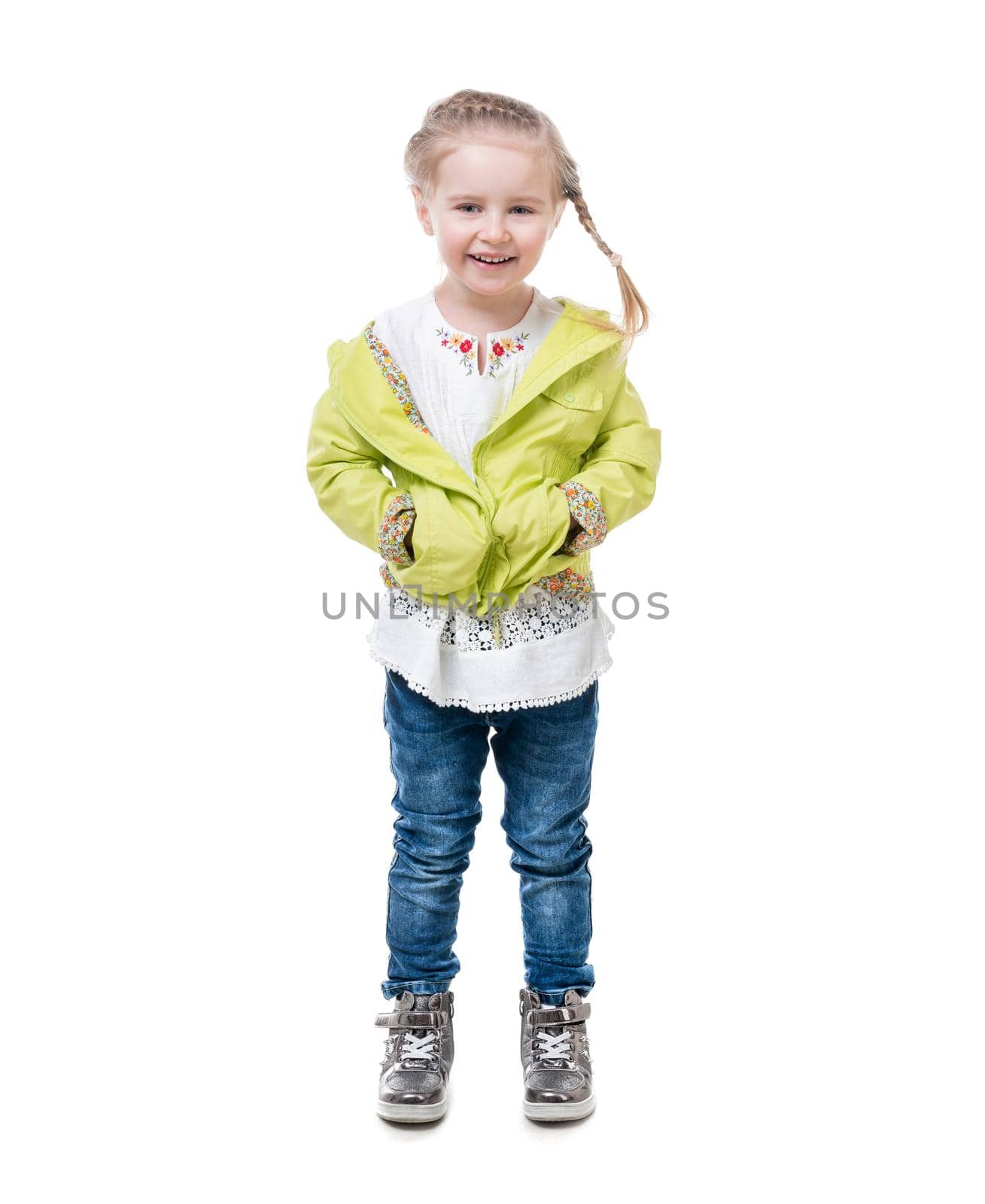 Little girl in a yellow jacket, silvery shirt standing, hugging herself, isolated on white background