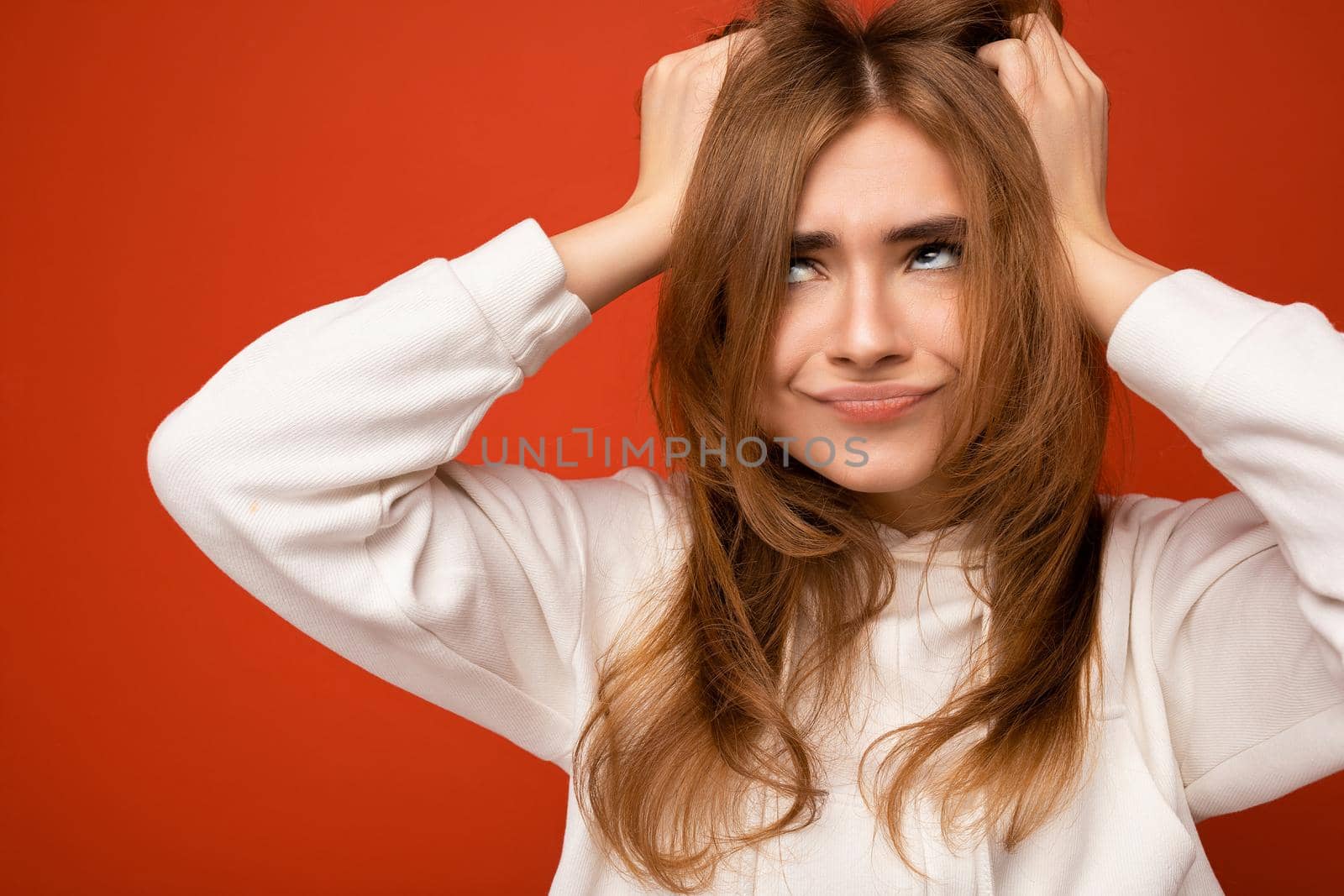 Photo of emotional sat adult beautiful dark blonde woman with sincere emotions isolated on background wall with copy space wearing casual white hoodie by TRMK