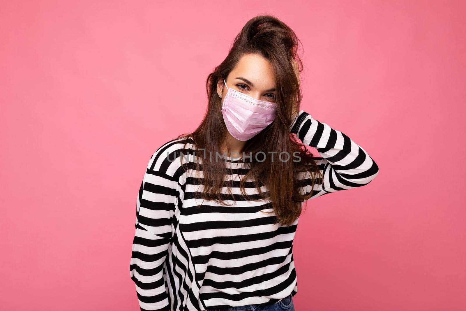 Shot of young attractive woman wearing mediacal face mask isolated over background wall. Protection against COVID-19.