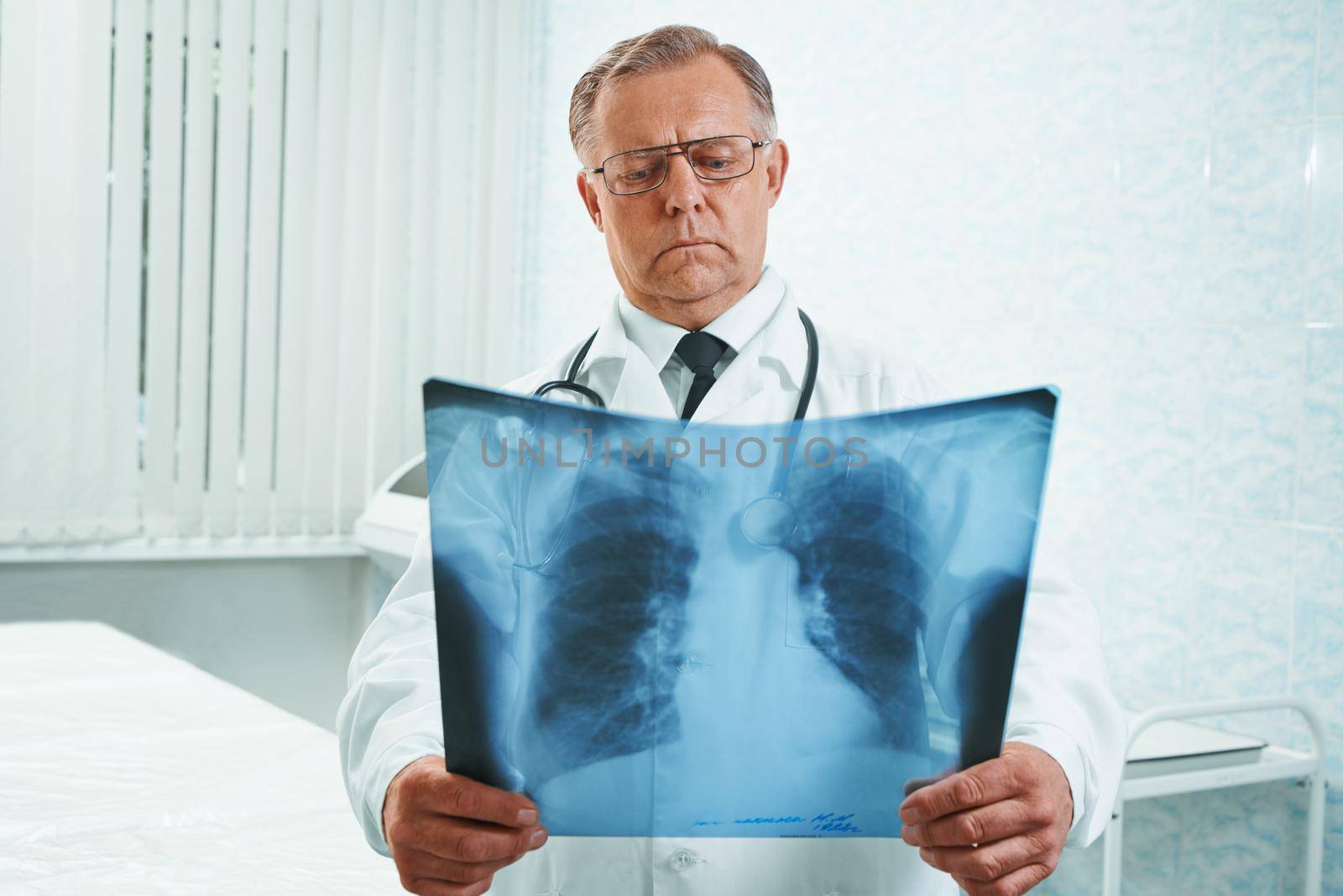 Older man doctor examines x-ray image of lungs in a hospital