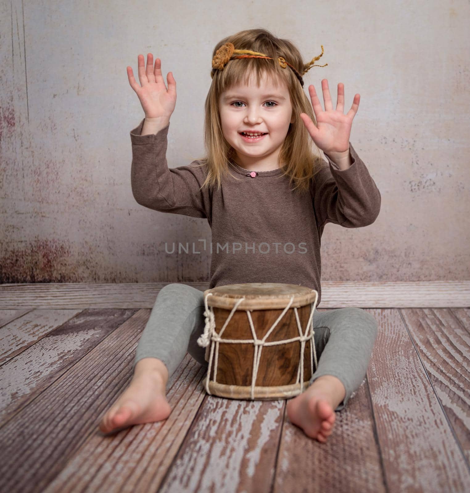 cute little girl with headband playing drum on the floor
