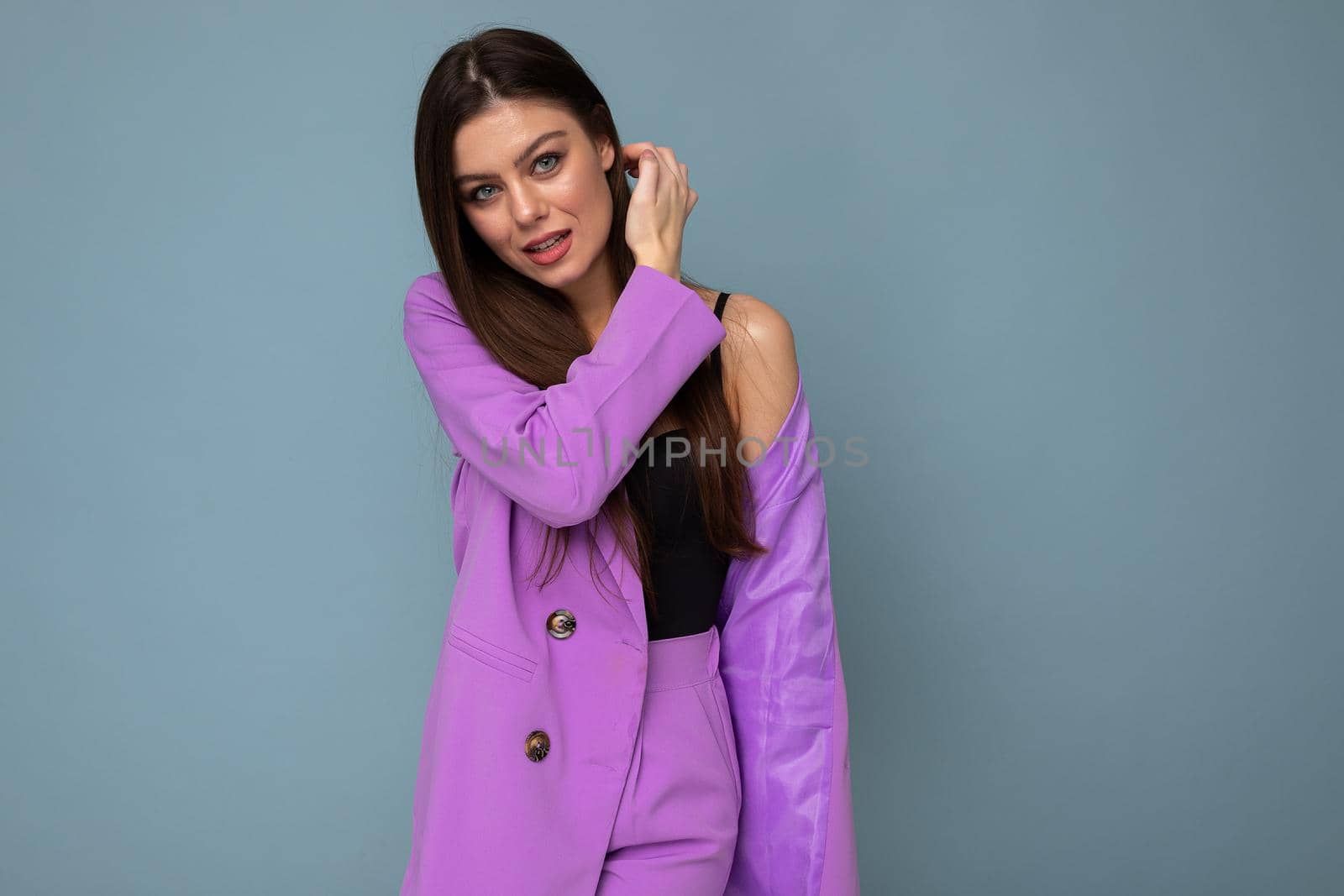 Photo of positive young business long hair brunette woman wearing purple suit isolated on blue background. Copy space.