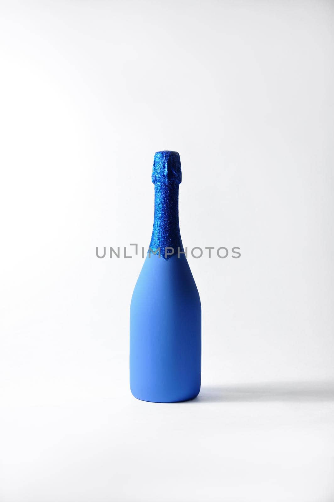 Festive Minimalistic Champagne Bottle on Light Background. Creative Concept. Classic Blue - Color of the year 2020.