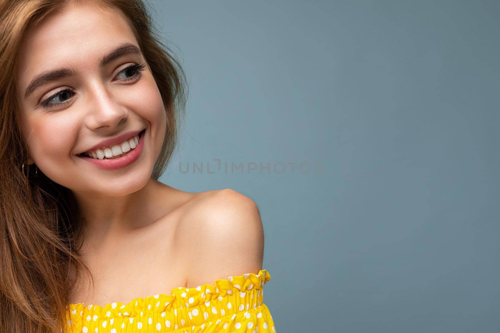 Closeup photo of young smiling cute beautiful dark blonde woman with sincere emotions isolated on background wall with copy space wearing stylish summer yellow dress. Positive concept.