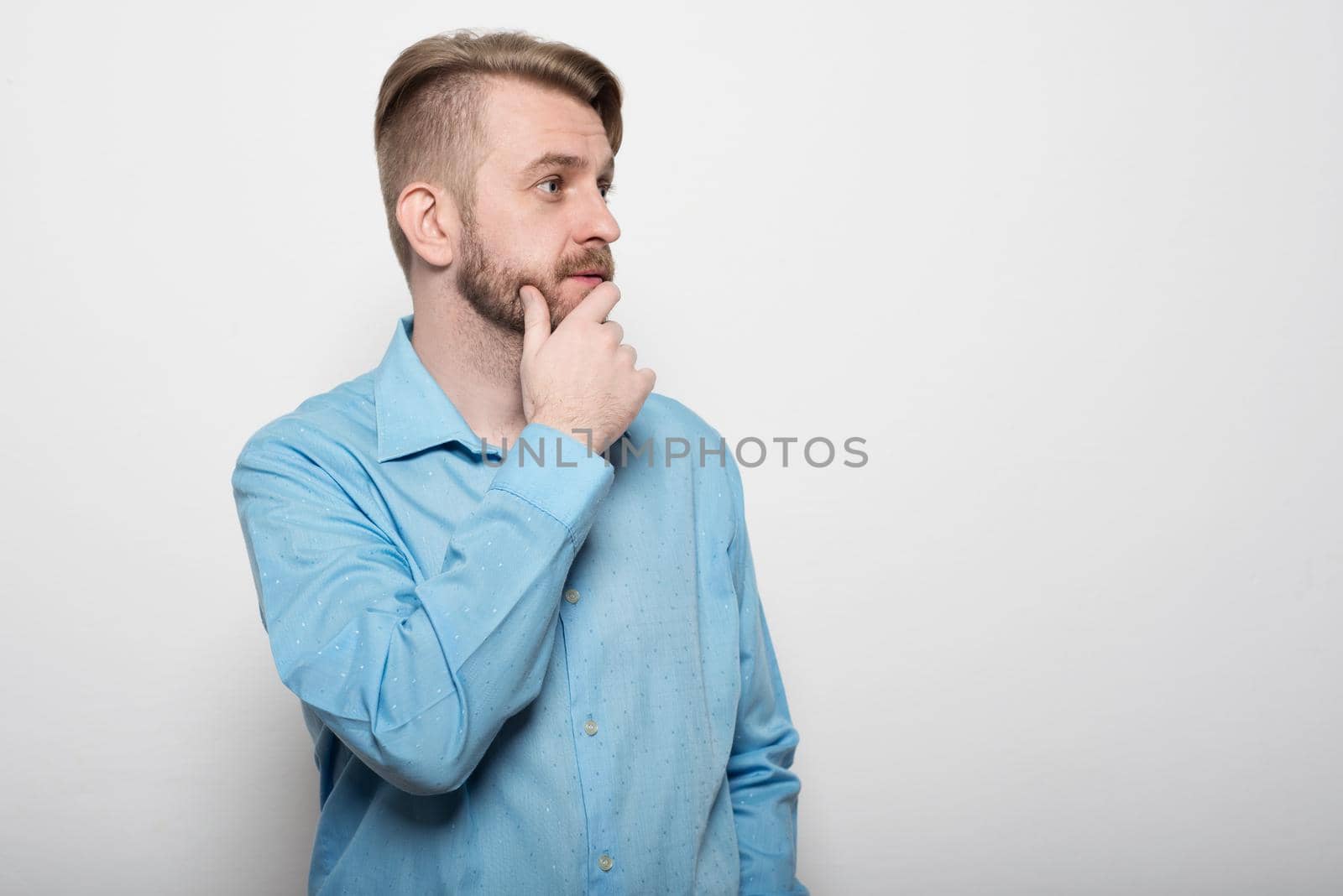 Portrait of a pensive businessman touching his chin over white background by zartarn