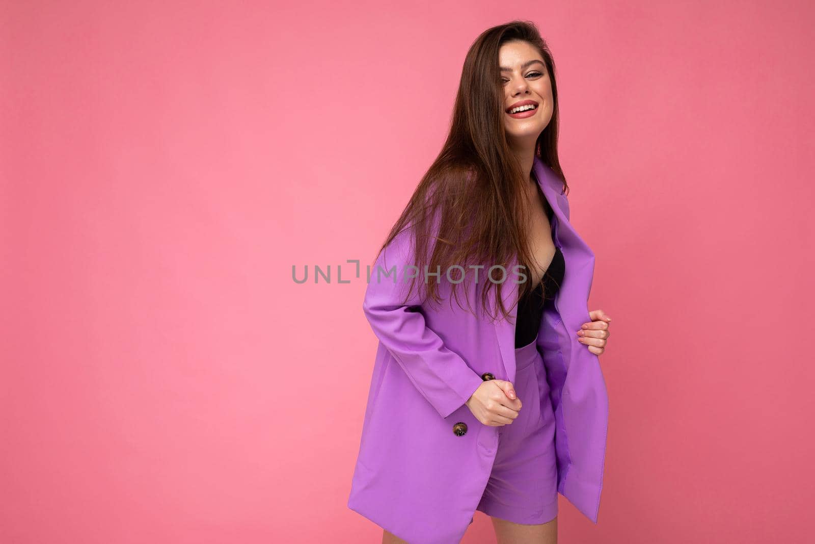 Young happy smiling brunette woman nice-looking attractive charming elegant fashionable wearing stylish suit with jacket isolated over pink background with copy space.