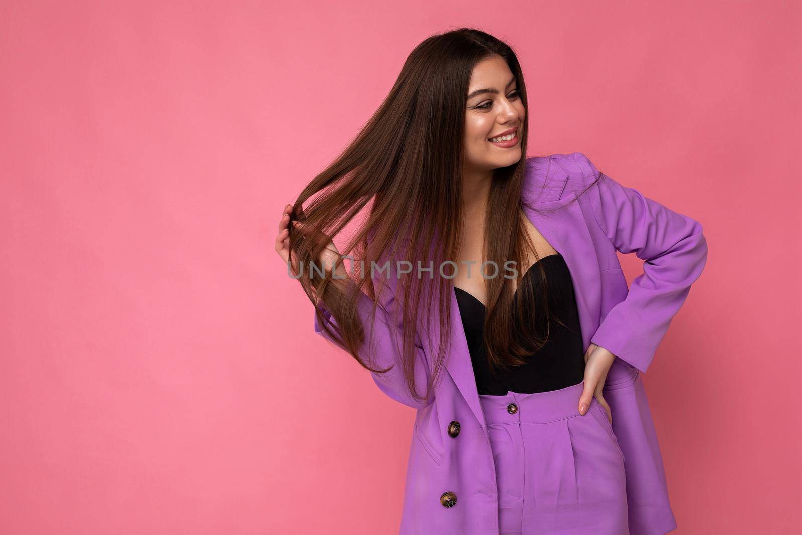 Young happy smiling brunette woman nice-looking attractive charming elegant fashionable wearing stylish suit with jacket isolated over pink background with copy space.