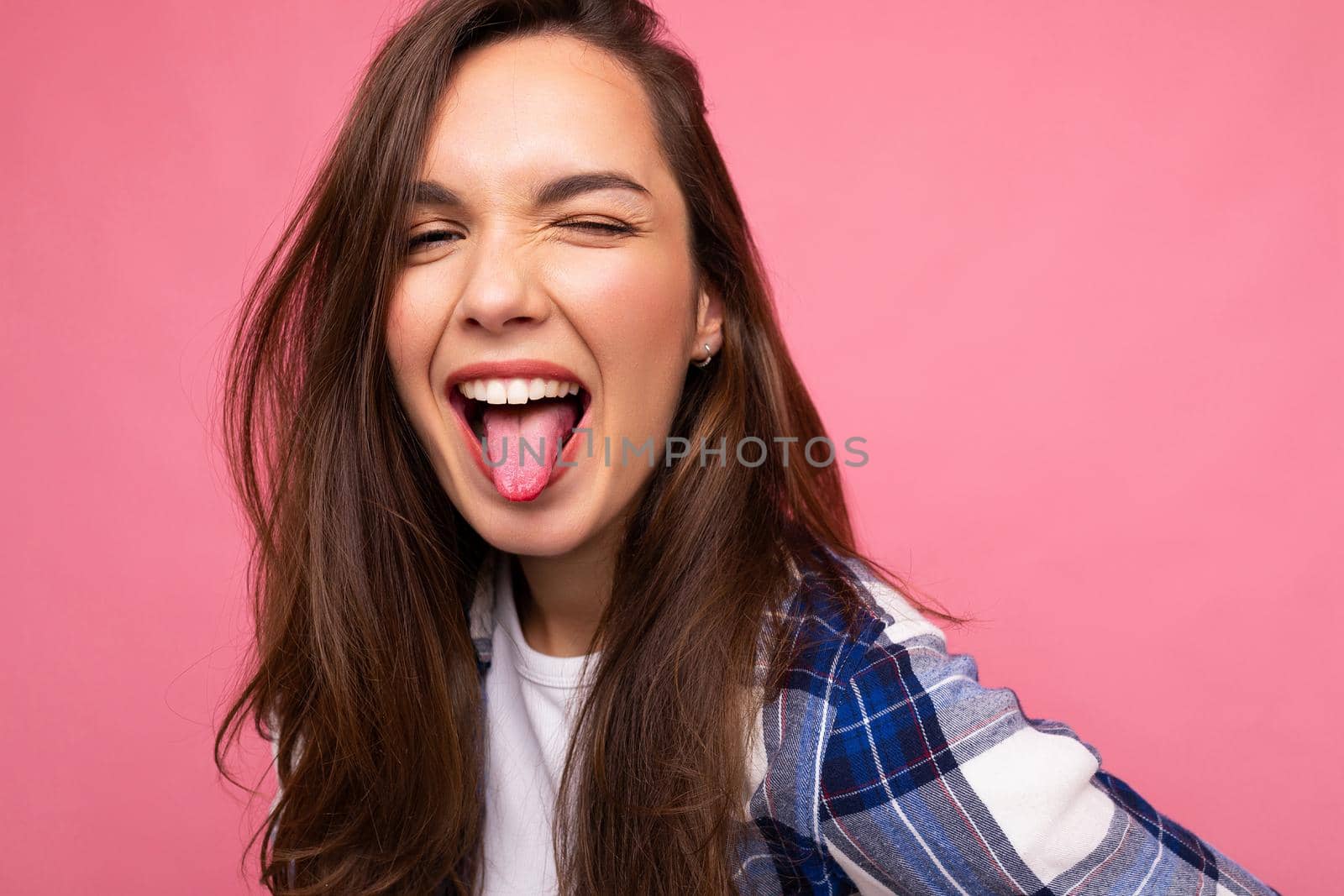 Photo shot of cute nice charming gorgeous attractive pretty youngster happy woman wearing stylish clothes isolated over colorful background with copy space showing tongue and having fun.