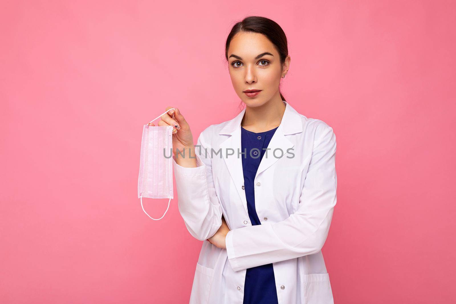 Caucasian woman showing protection face mask isolated on pink background. Coronavirus or Covid-19 Concept.