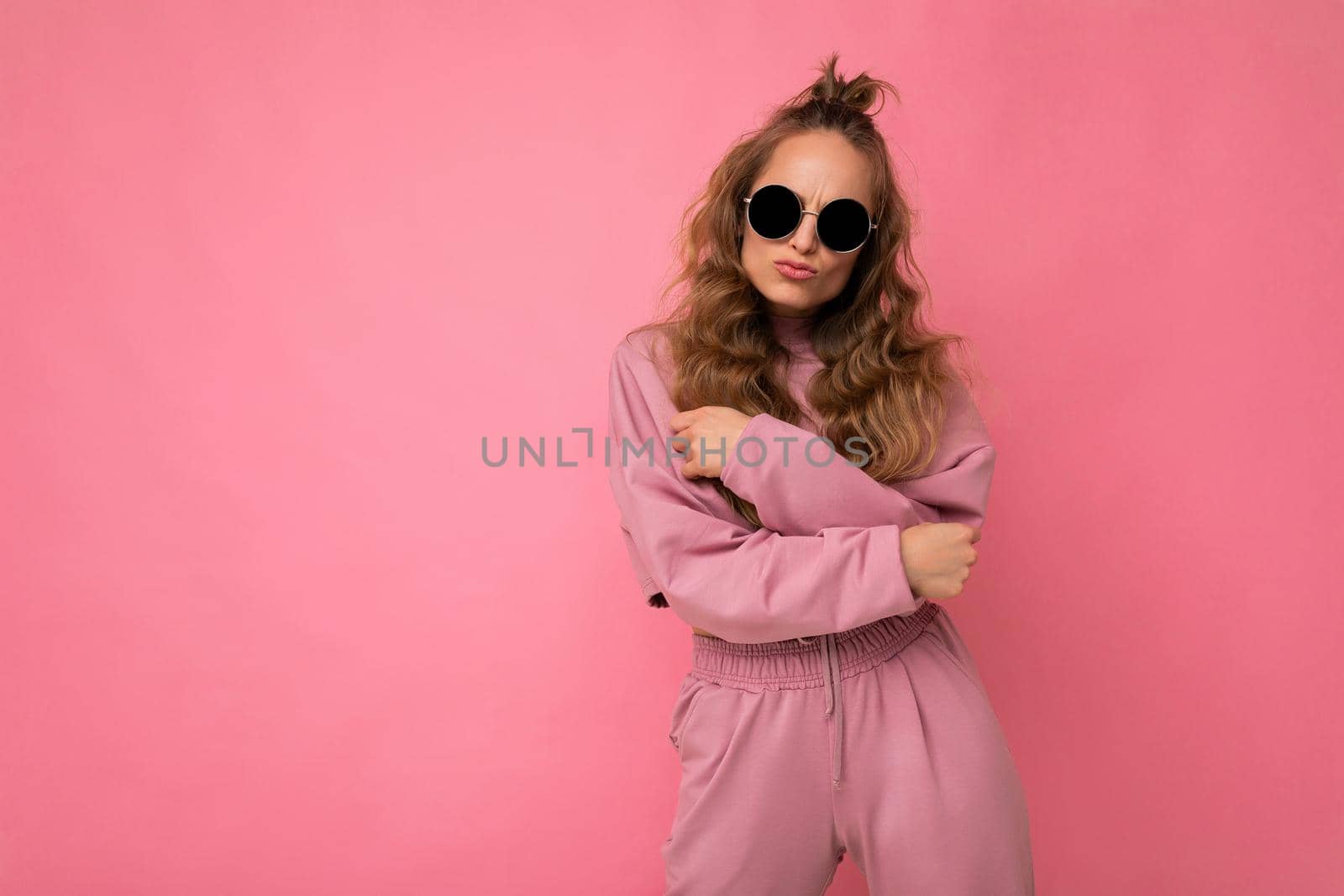 Photo shot of beautiful positive young dark blonde woman wearing casual clothes and stylish sunglasses isolated over colorful background looking at camera. empty space