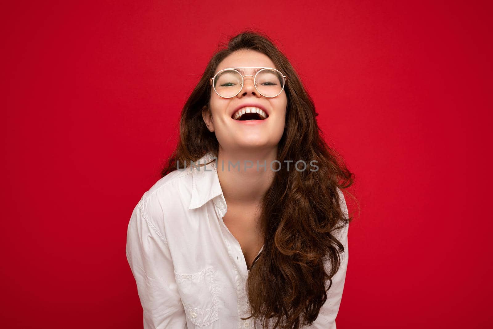 Photo shot of beautiful positive young brunette woman wearing casual clothes and stylish optical glasses isolated over colorful background wall looking at camera.