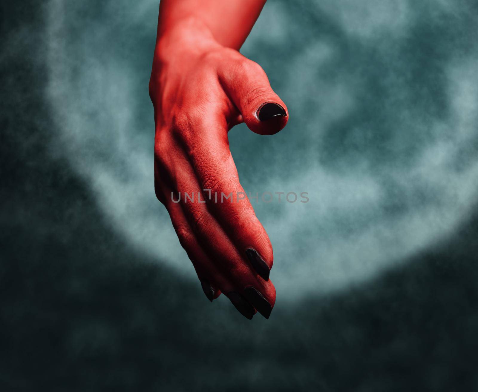 Red demon hand with handshake gesture on background of full moon. Halloween or horror theme