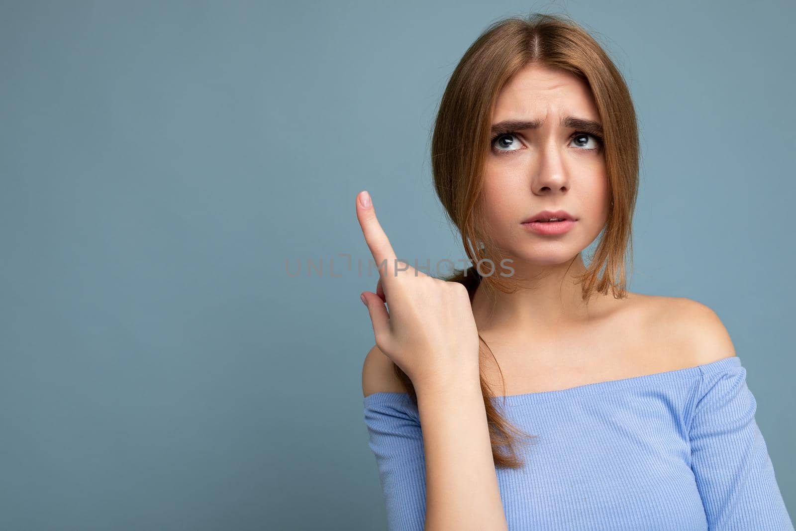 Photo portrait of moody thoughtful young nice beautiful blonde woman with sincere emotions wearing trendy blue crop top isolated over background with empty space and thinking with doubts.